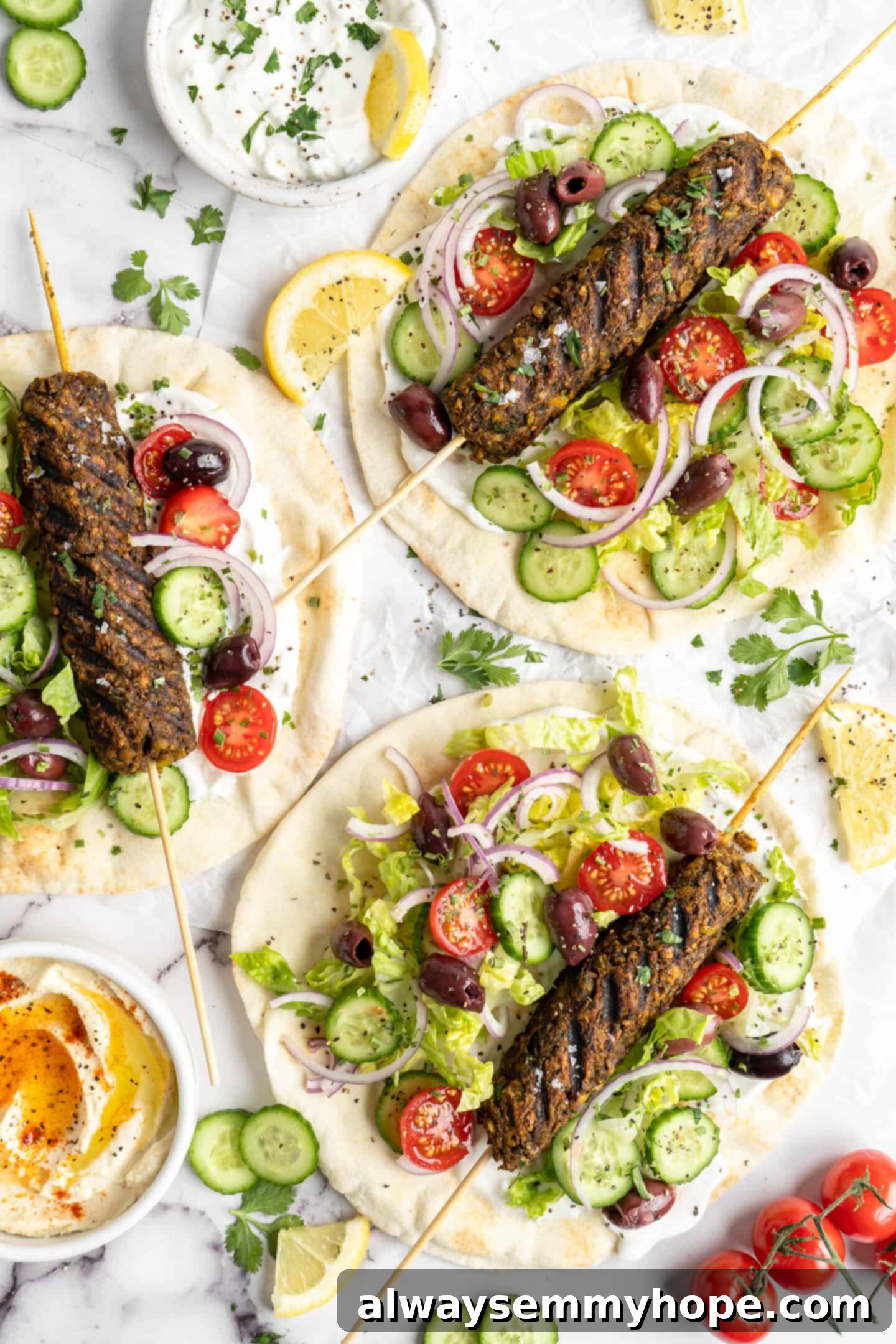 Overhead view of grilled vegan kofta skewers served on fluffy pita bread, garnished with fresh vegetables like red onion, tomatoes, and cucumbers, drizzled with creamy tahini sauce or vegan tzatziki.