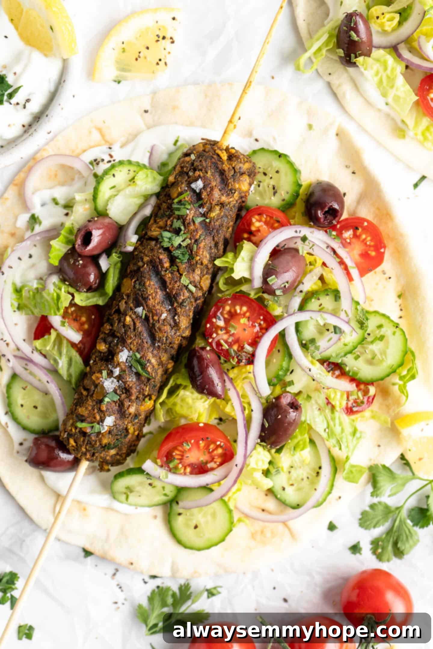 A beautifully plated vegan kofta meal on pita bread, surrounded by fresh cucumber slices, cherry tomatoes, olives, and thinly sliced red onion, highlighting a complete and vibrant dish.