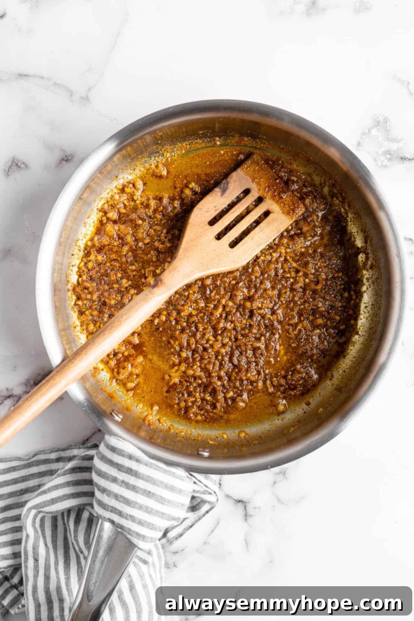Shallots and garlic sautéing in olive oil in a skillet, with various Middle Eastern spices ready to be added, creating an aromatic base for the vegan kofta.