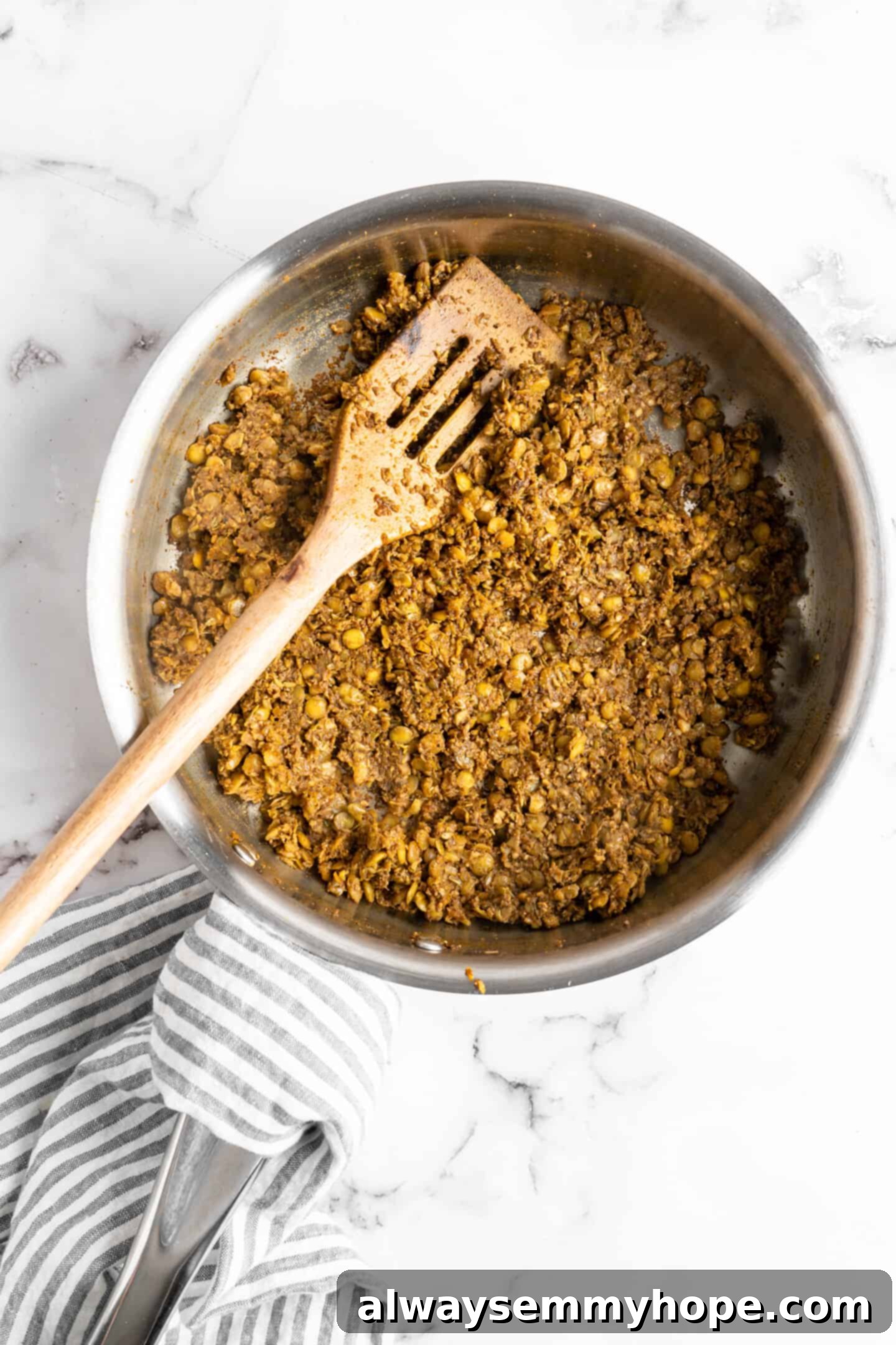 The finished vegan kofta mixture in a skillet, rich and brown, being stirred with a wooden spatula.