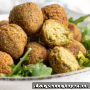 Crunchy Homemade Falafel 2 Closeup of falafel in bowl with greens, with one cut open to show fluffy inside