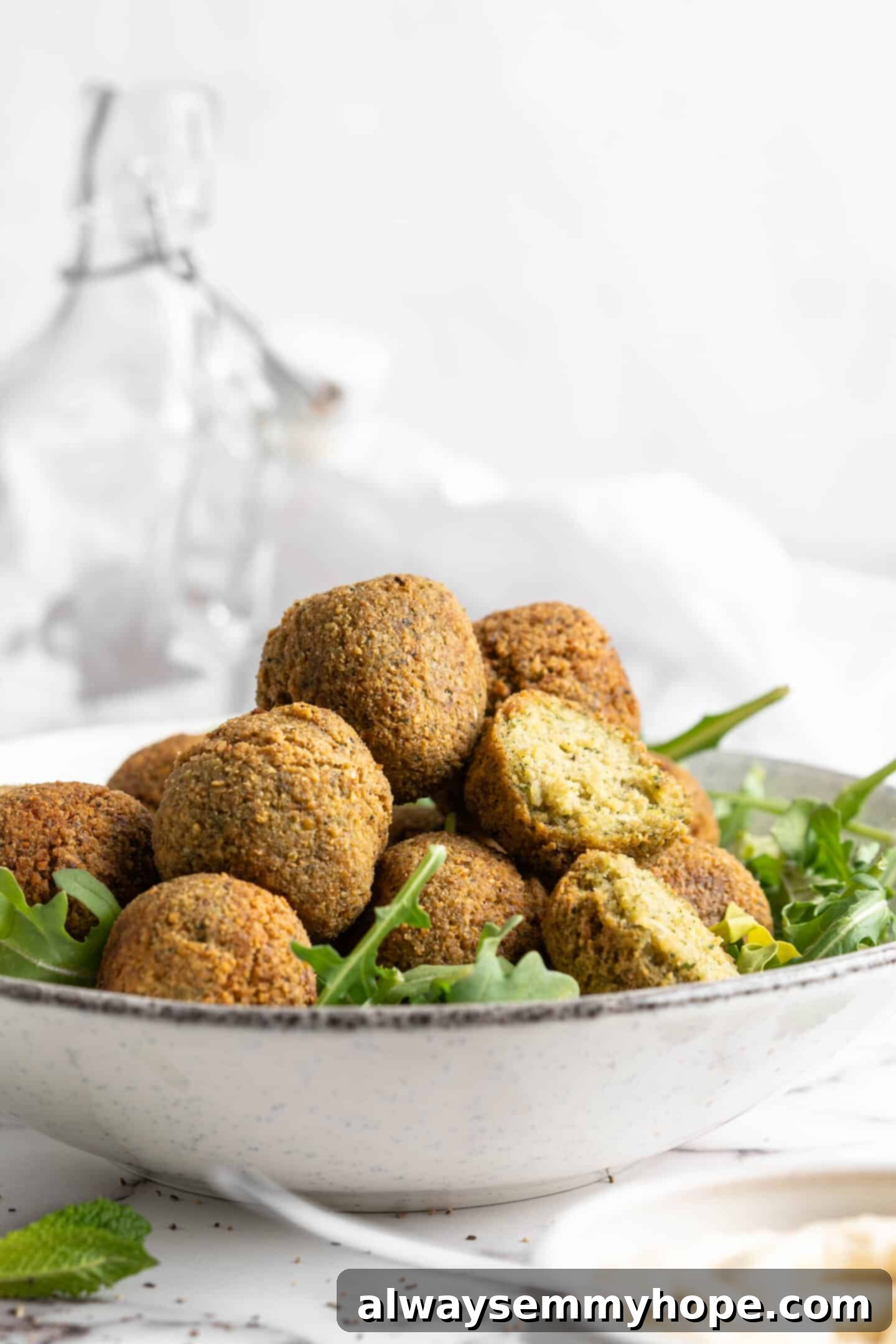 This homemade falafel recipe is just like the kind they make at restaurants. Fluffy on the inside, crispy on the outside, and so delicious! Bowl of greens topped with homemade falafel