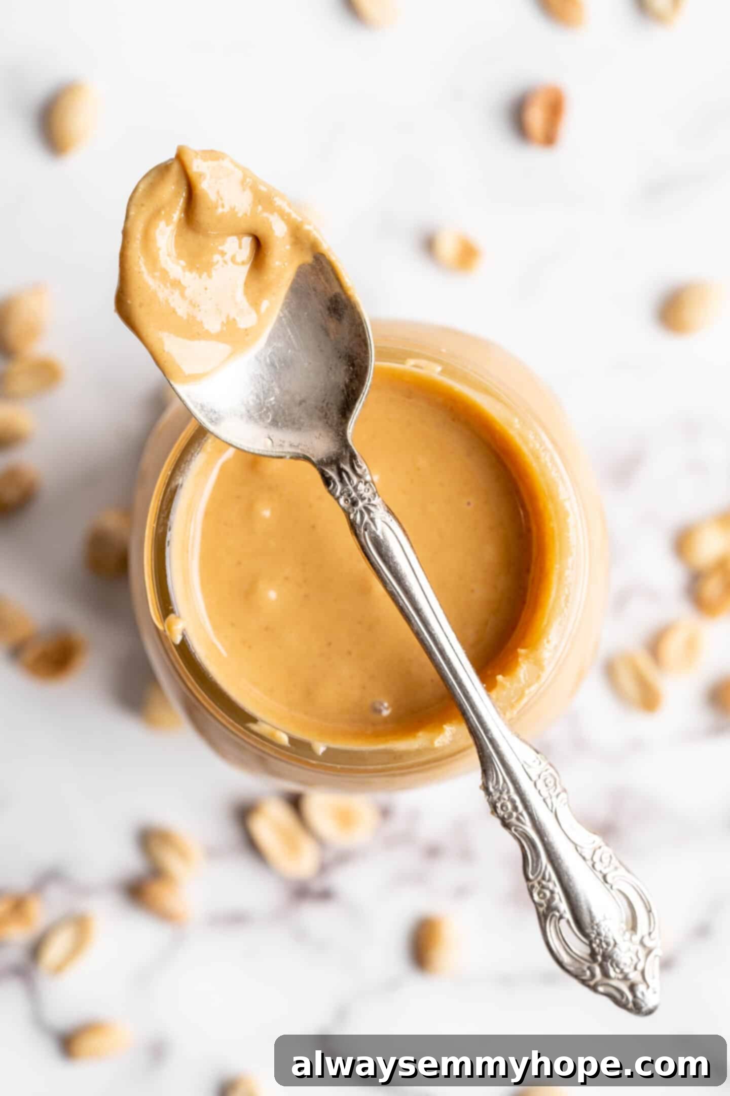 Overhead view of spoon of peanut butter set on jar