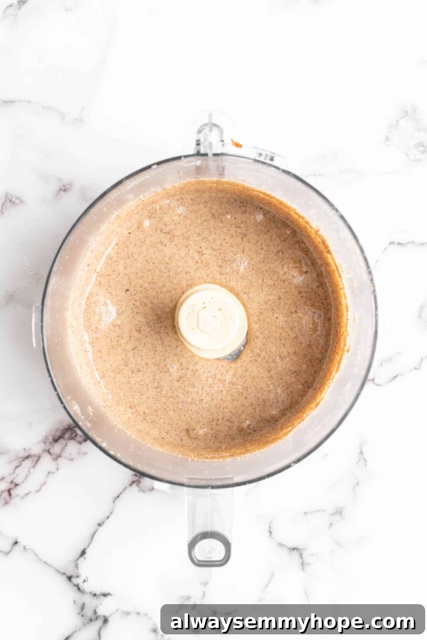 Overhead view of smooth, creamy almond butter in a food processor bowl