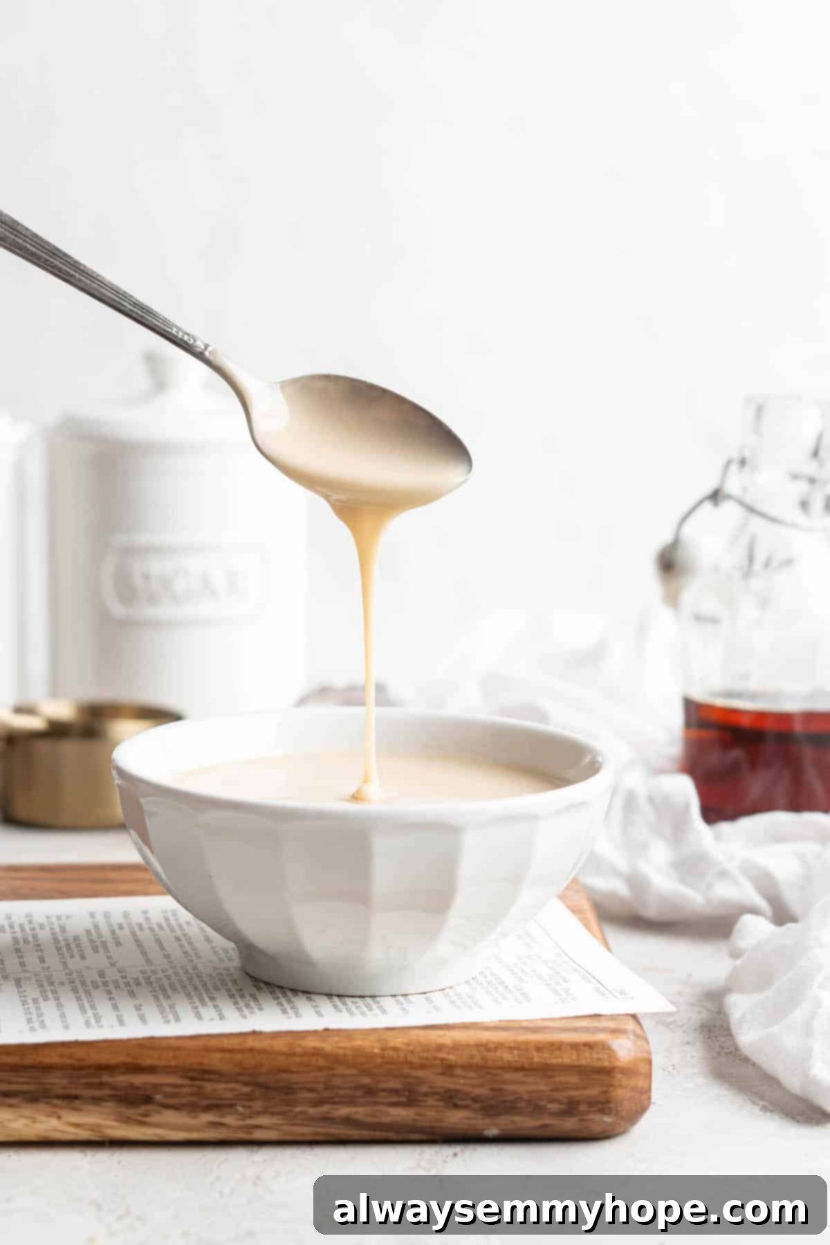 Spoon drizzling thick, creamy homemade vegan condensed milk into a bowl, showcasing its rich texture, perfect for plant-based desserts and baking