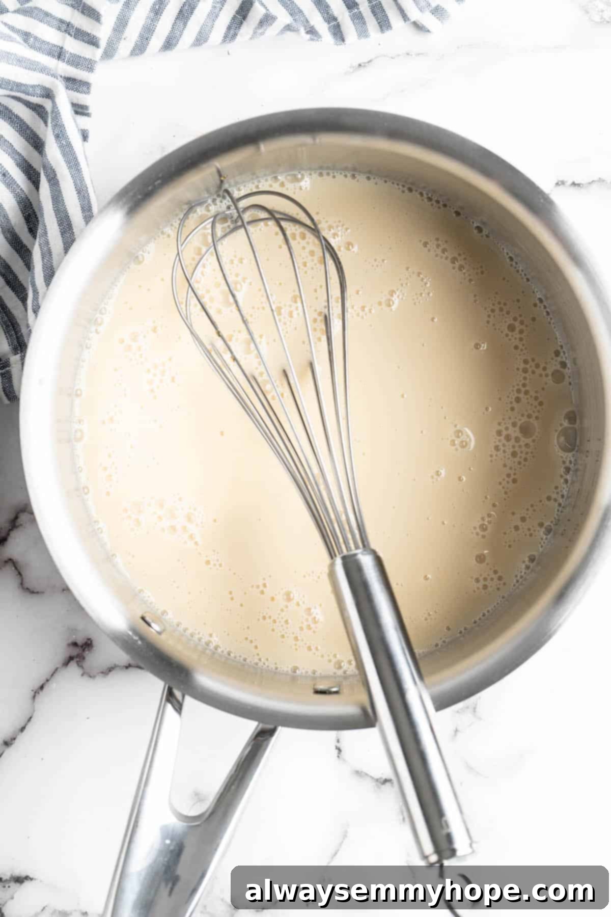 Vegan condensed milk simmering gently in a pan with a whisk, reducing and thickening on low heat
