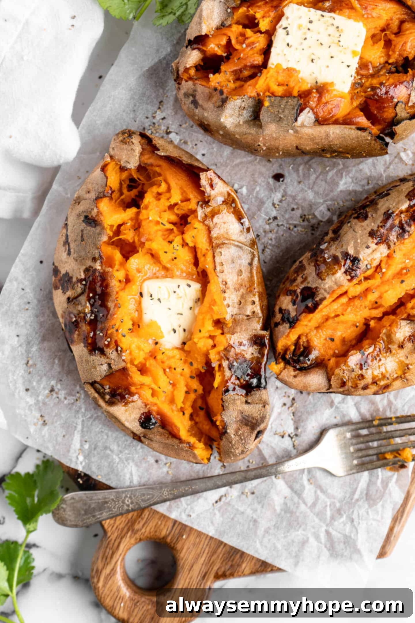 Overhead view of air fryer baked sweet potatoes topped with a pat of butter.