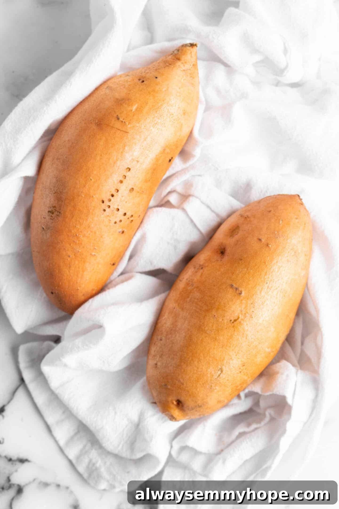 Two sweet potatoes on a kitchen towel.