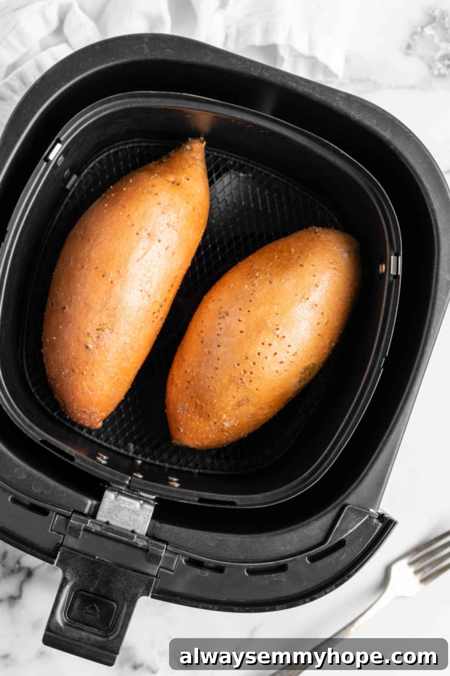 Two sweet potatoes in an air fryer.