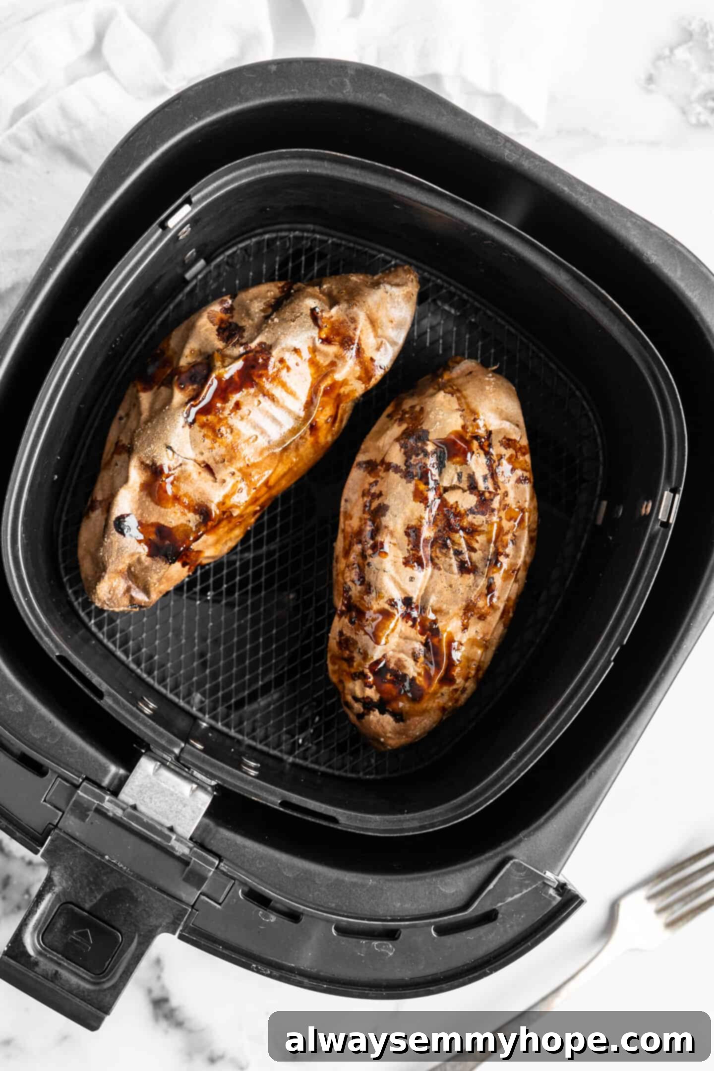 Two baked sweet potatoes in an air fryer.
