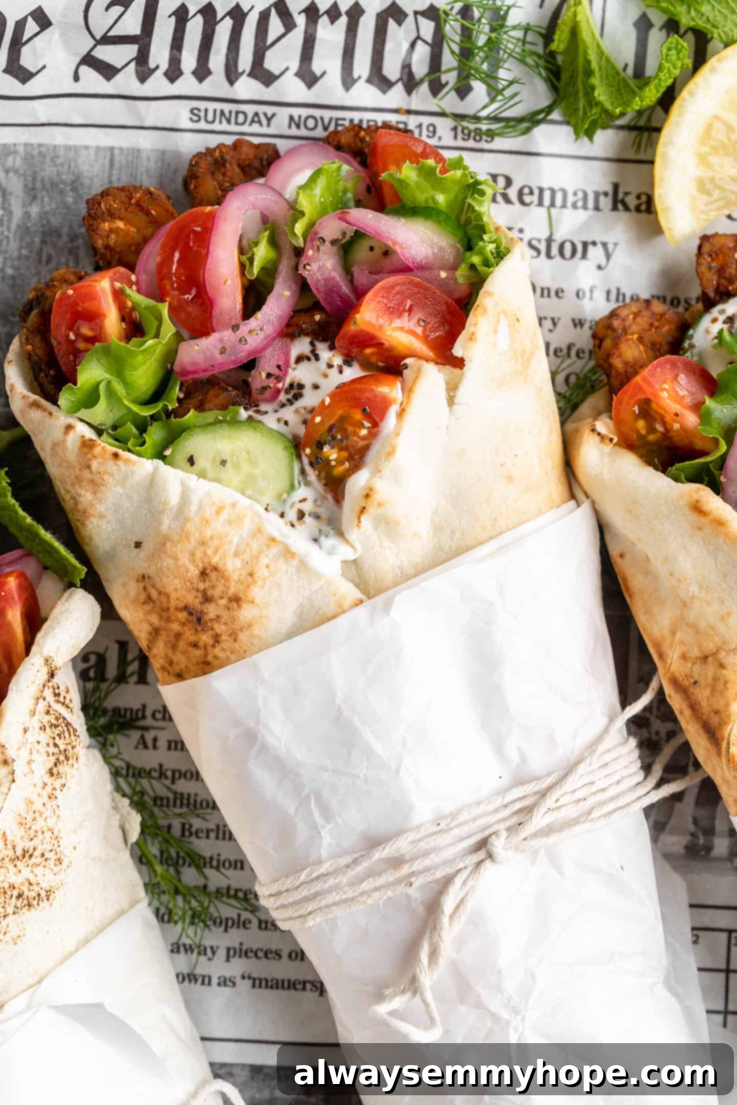 A perfectly wrapped vegan tempeh gyro, neatly secured with parchment paper and string, ready to be enjoyed.
