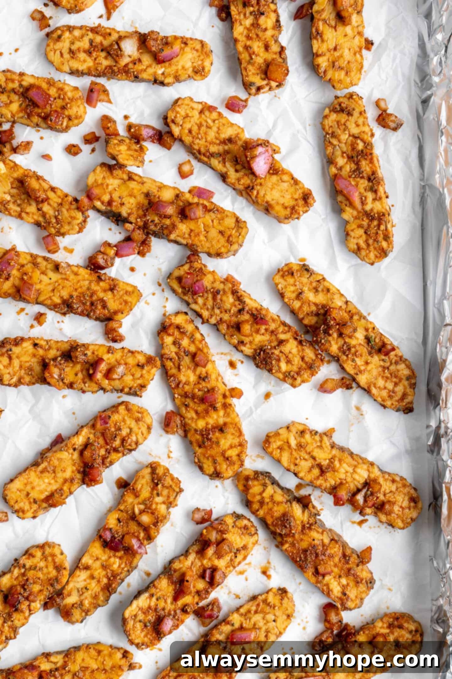 Marinated vegan tempeh gyros strips arranged neatly on a parchment-lined baking sheet, ready for roasting.
