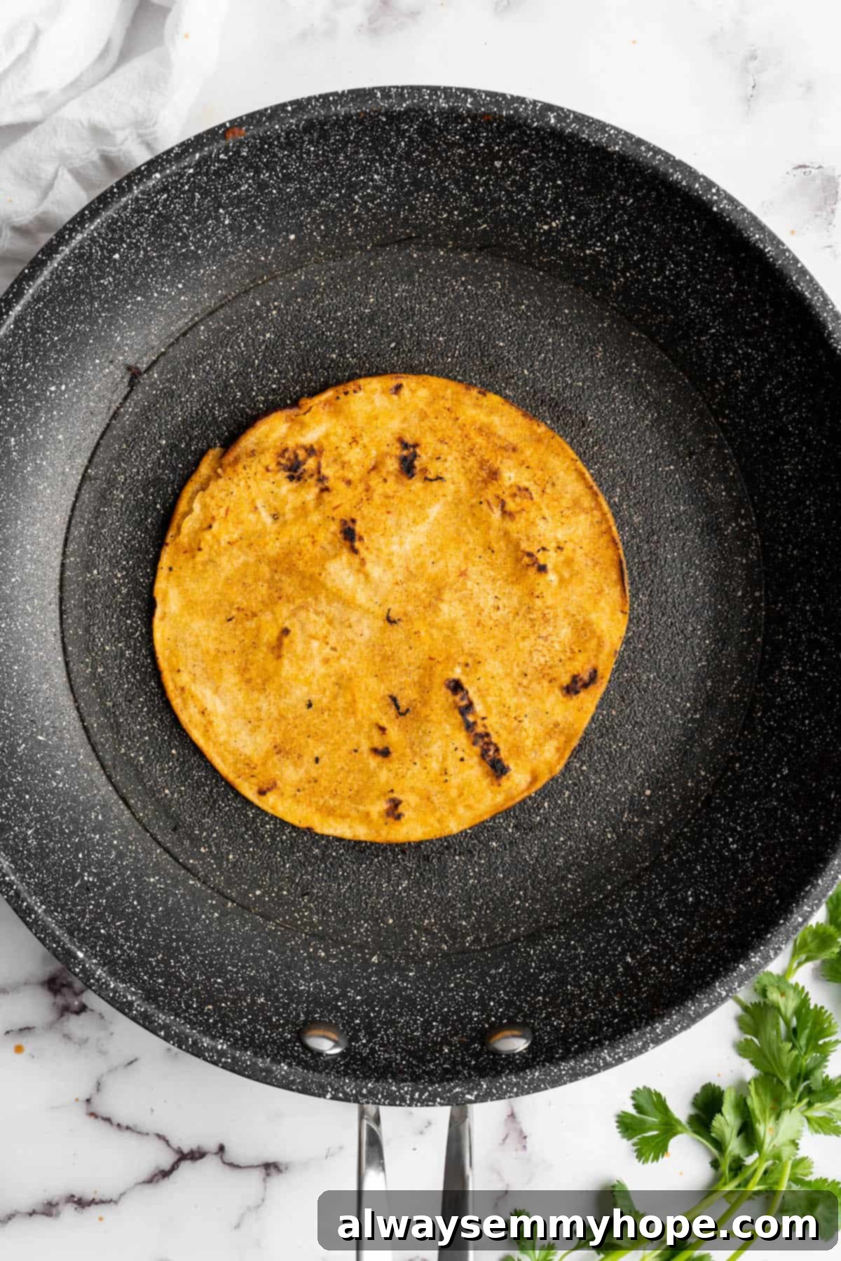Vegan birria tacos use king oyster mushrooms to mimic the texture/flavour of the original. They’re smoky, crispy, and perfect for dipping! Overhead view of a corn tortilla in a skillet.