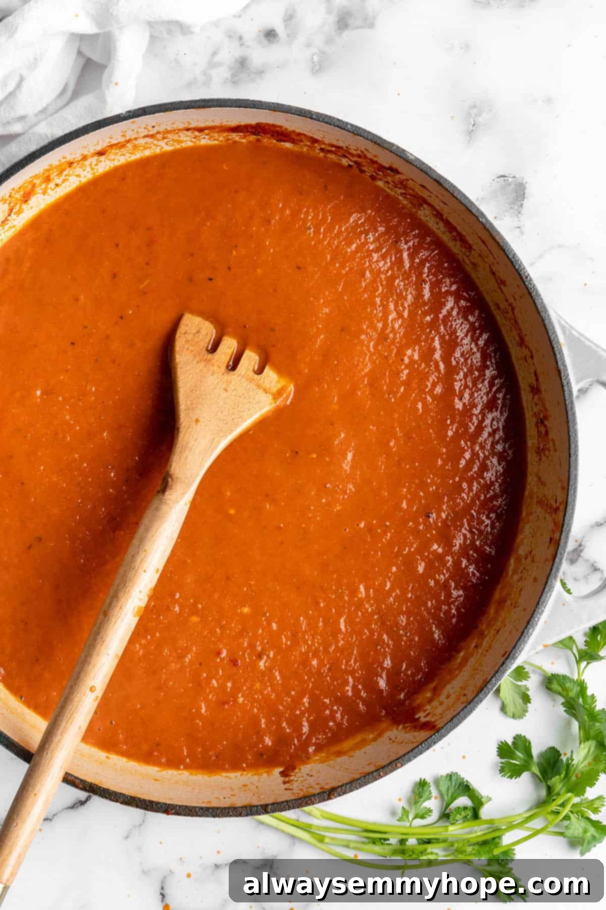 Vegan birria tacos use king oyster mushrooms to mimic the texture/flavour of the original. They’re smoky, crispy, and perfect for dipping! Overhead view of birria sauce in a pot with a wooden spoon.