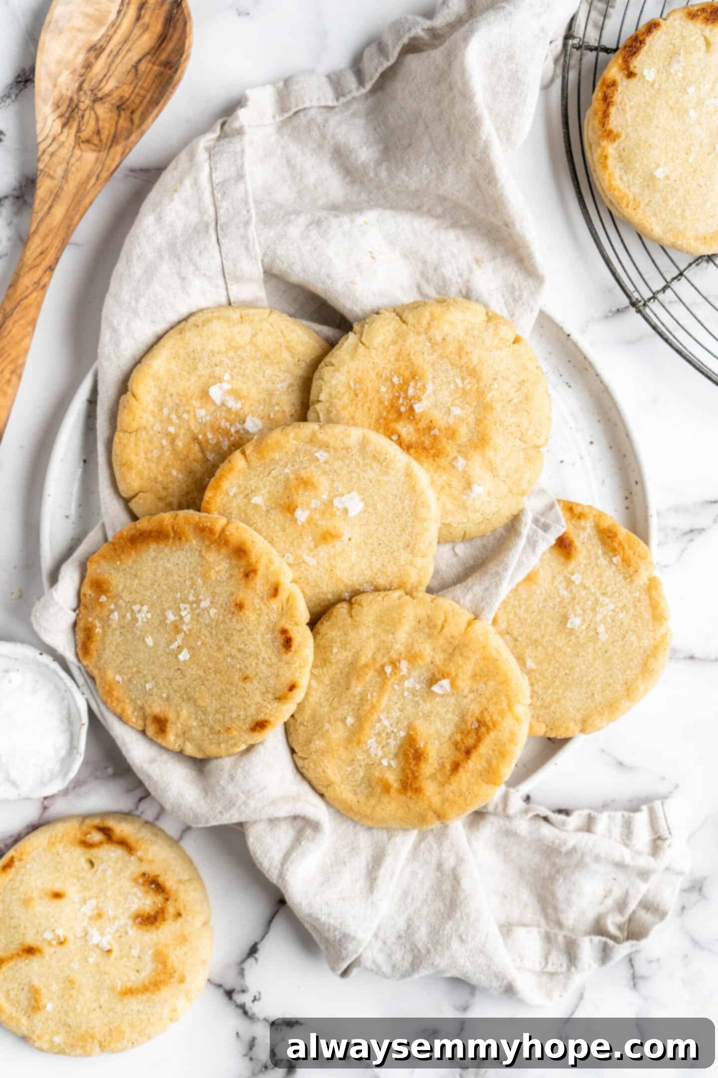 This step-by-step tutorial will show you how to make perfect vegan arepas with just a few ingredients. They're easier to make than you think! Overhead shot of a stack of freshly made vegan arepas on a rustic tea towel, showcasing their perfect texture and golden hue.