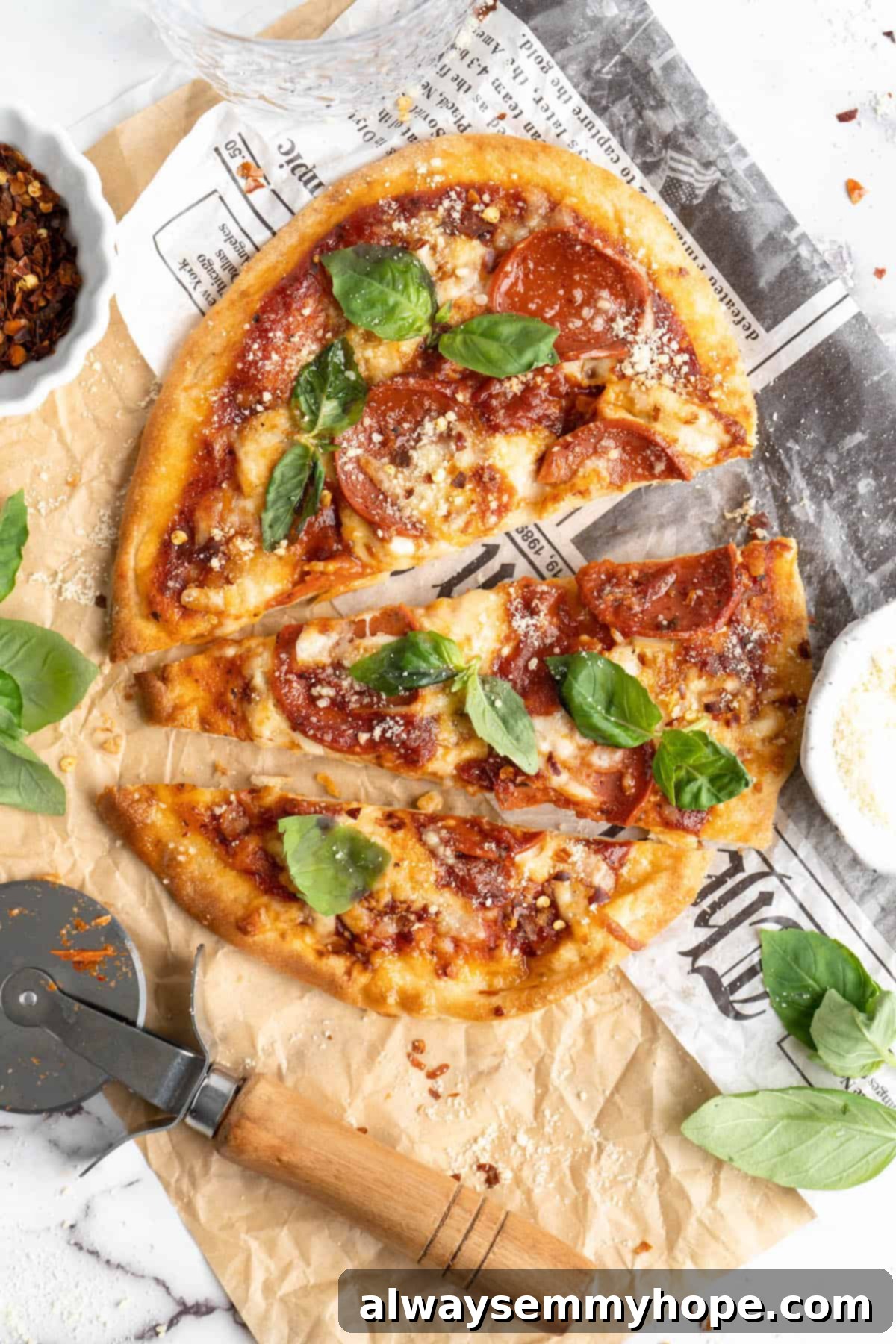 Overhead view of two vegan naan pizzas, one sliced into thirds, garnished with fresh basil.