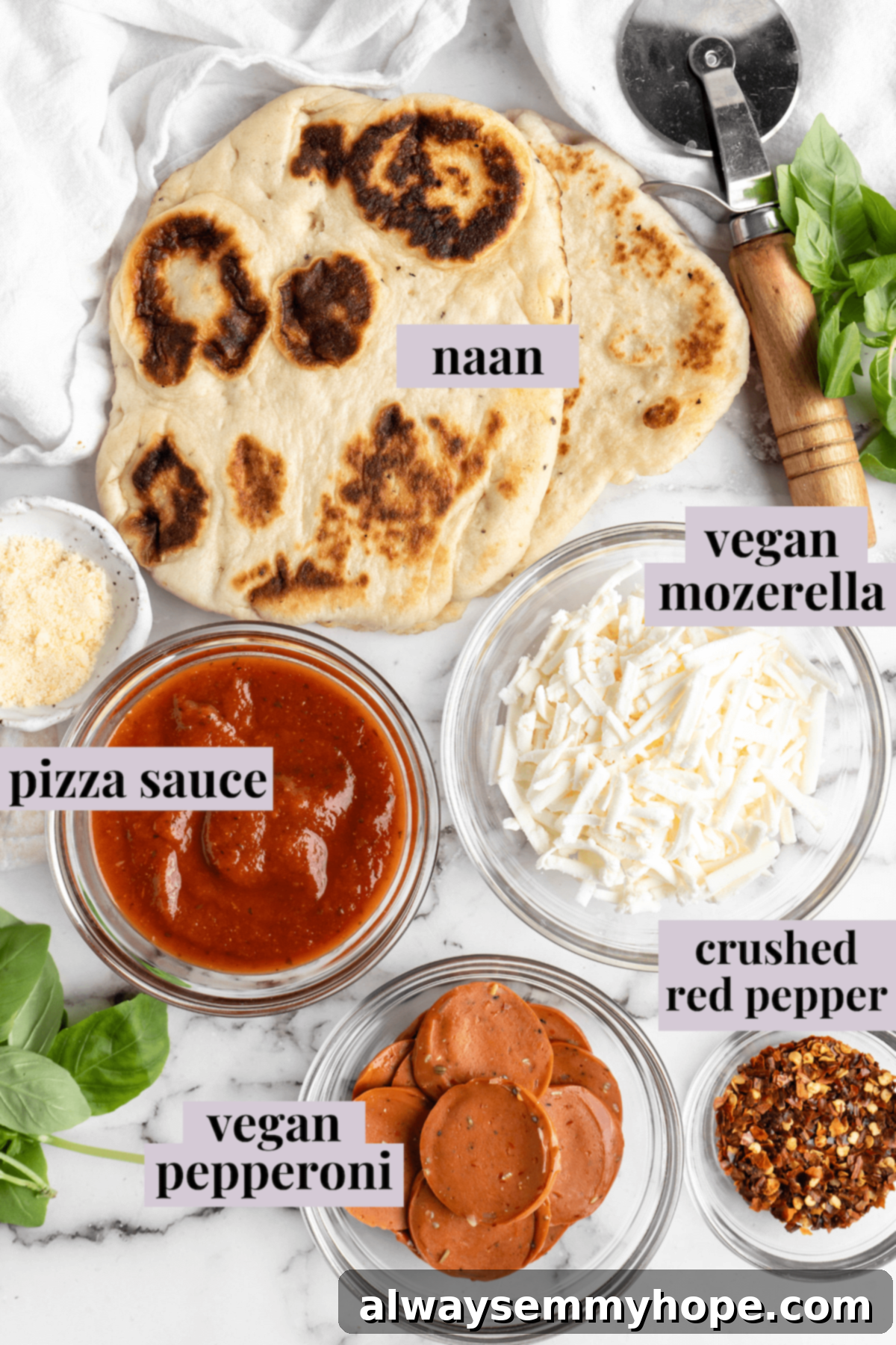 Overhead view of all ingredients for vegan naan pizza, neatly arranged and labeled on a kitchen counter.