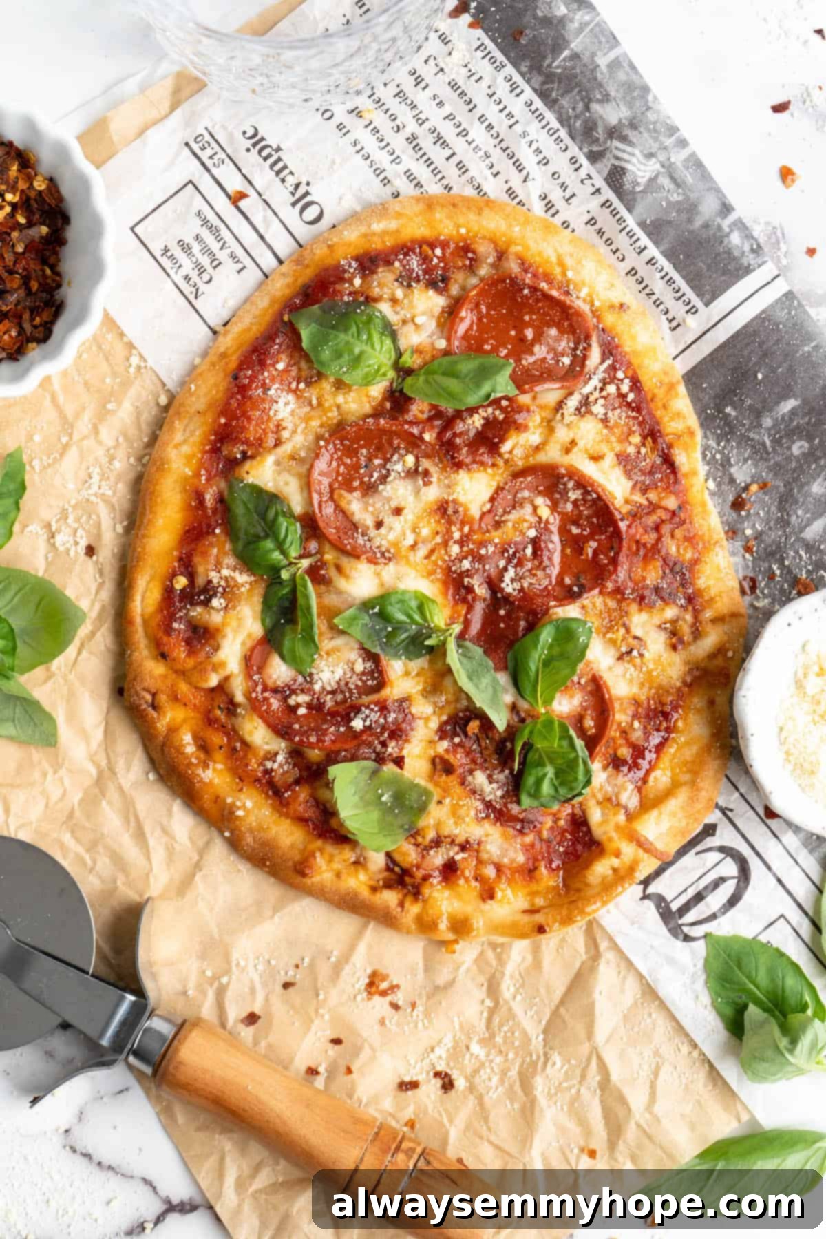 Overhead view of a whole vegan naan pizza, beautifully garnished with fresh basil leaves, on a wooden board.
