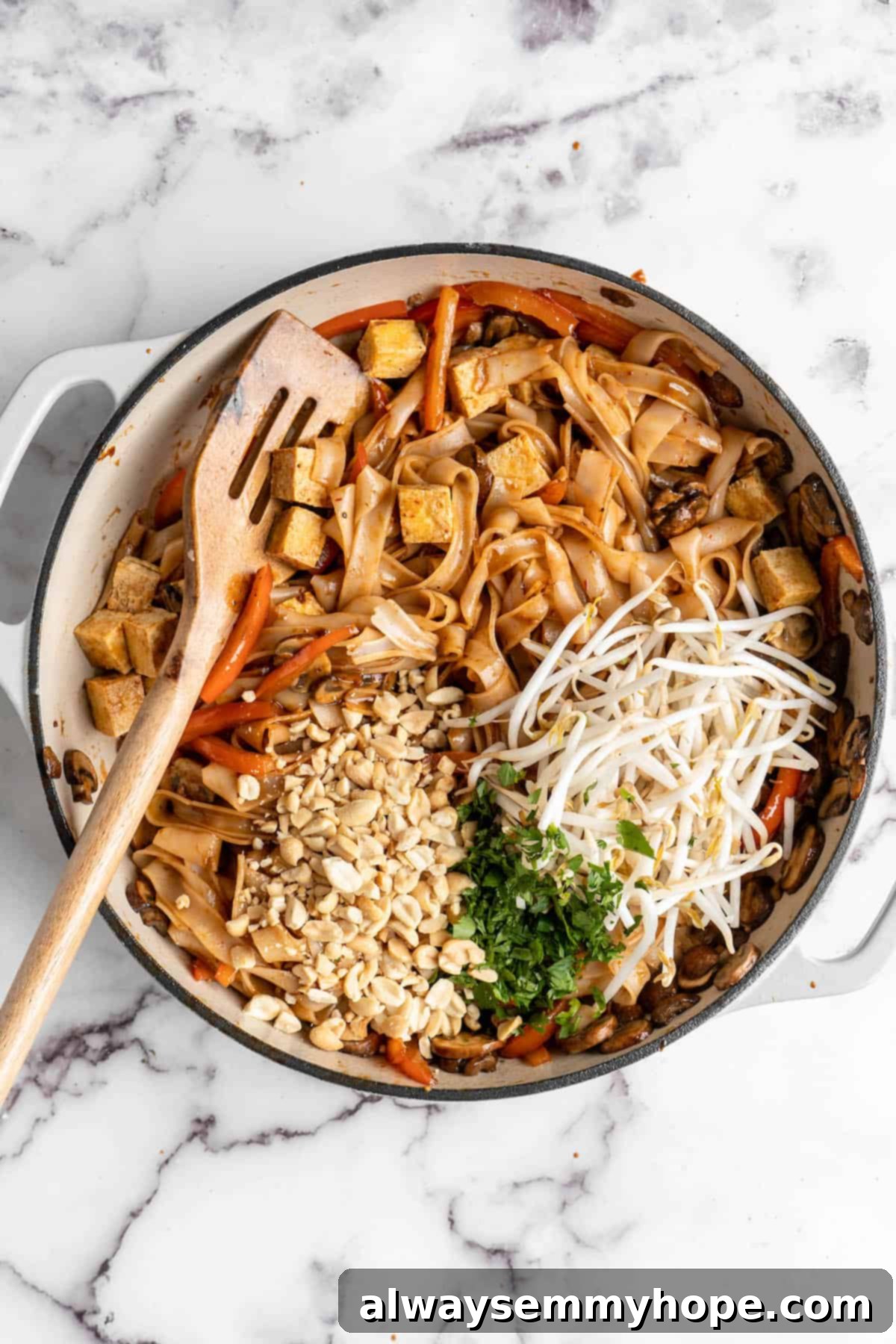 Overhead view of Pad Thai in skillet after adding peanuts, cilantro, and sprouts
