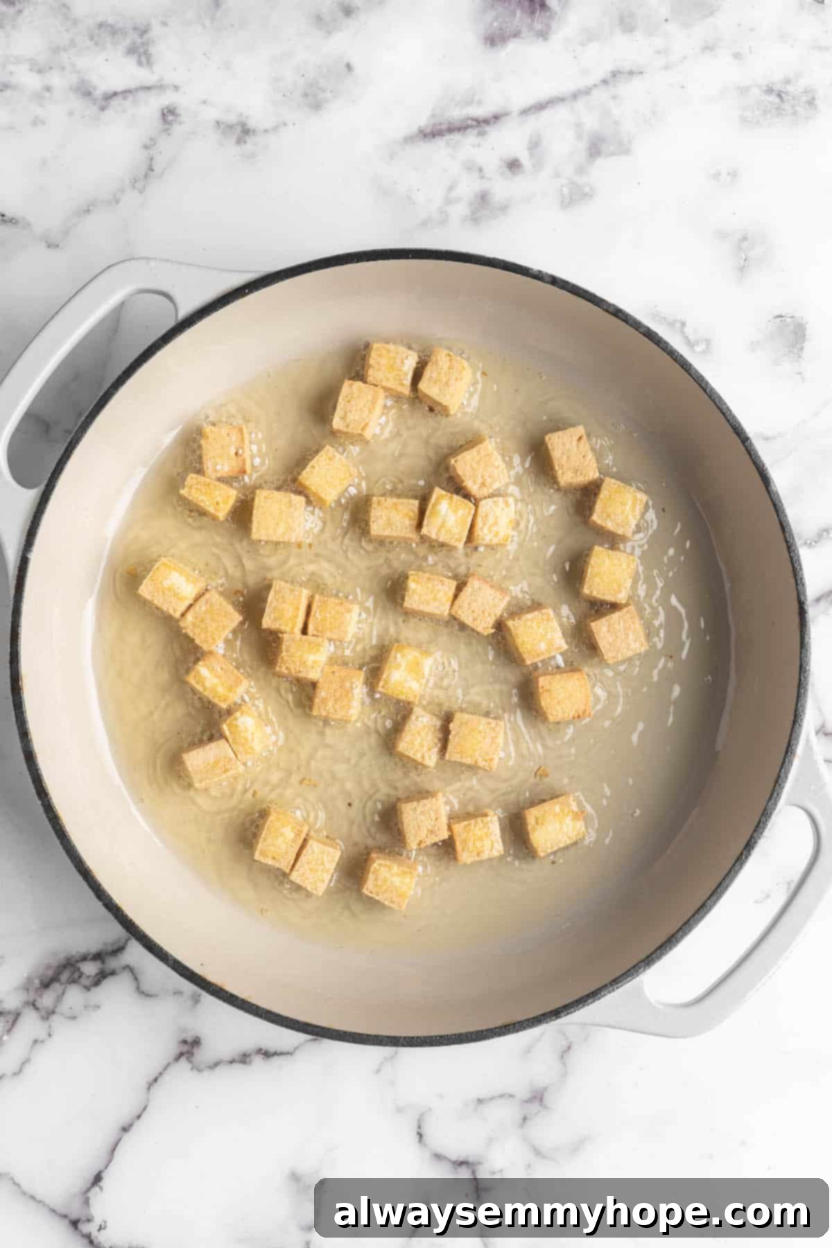 Overhead view of tofu cubes in skillet with oil