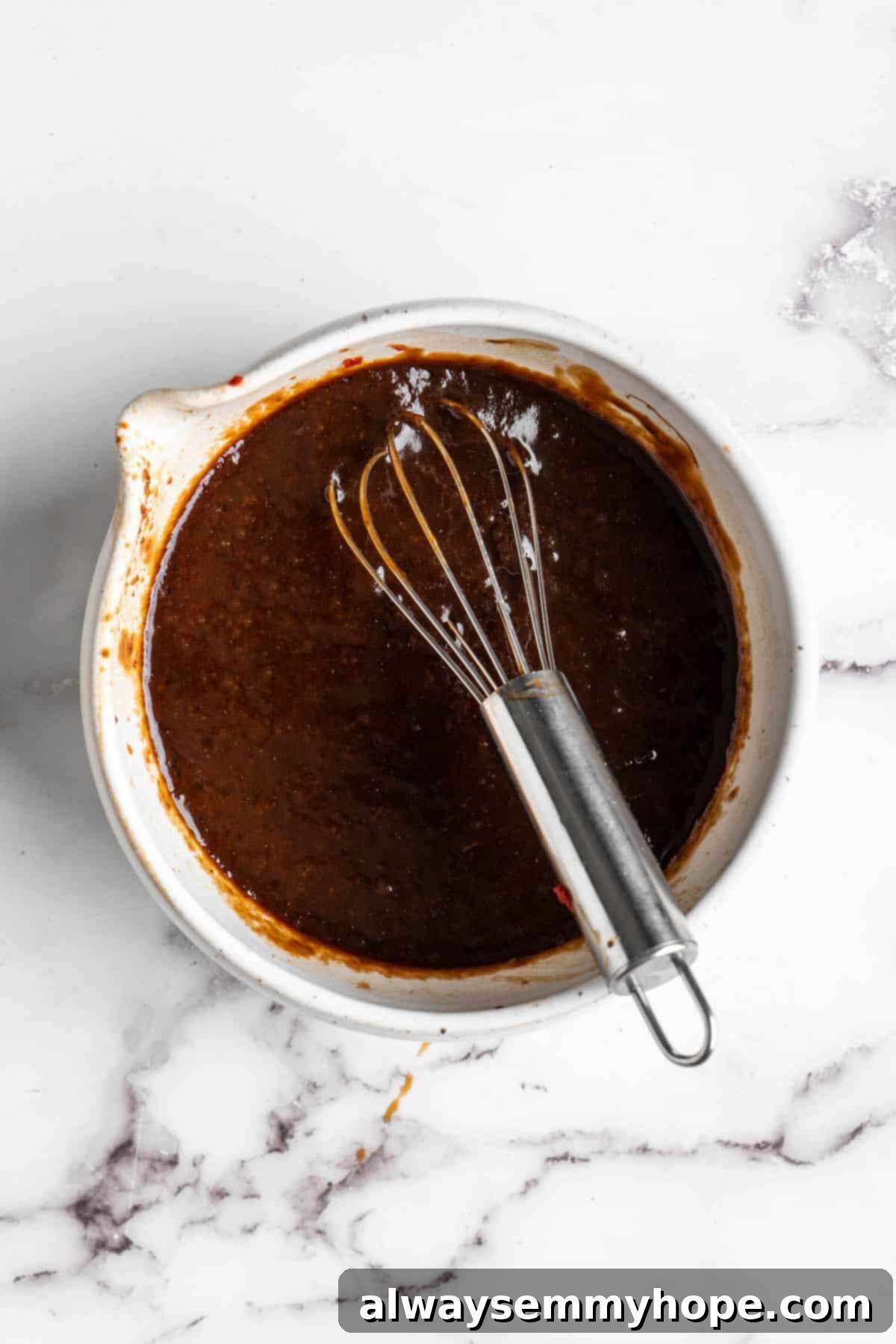 Overhead view of pad Thai sauce in bowl with whisk