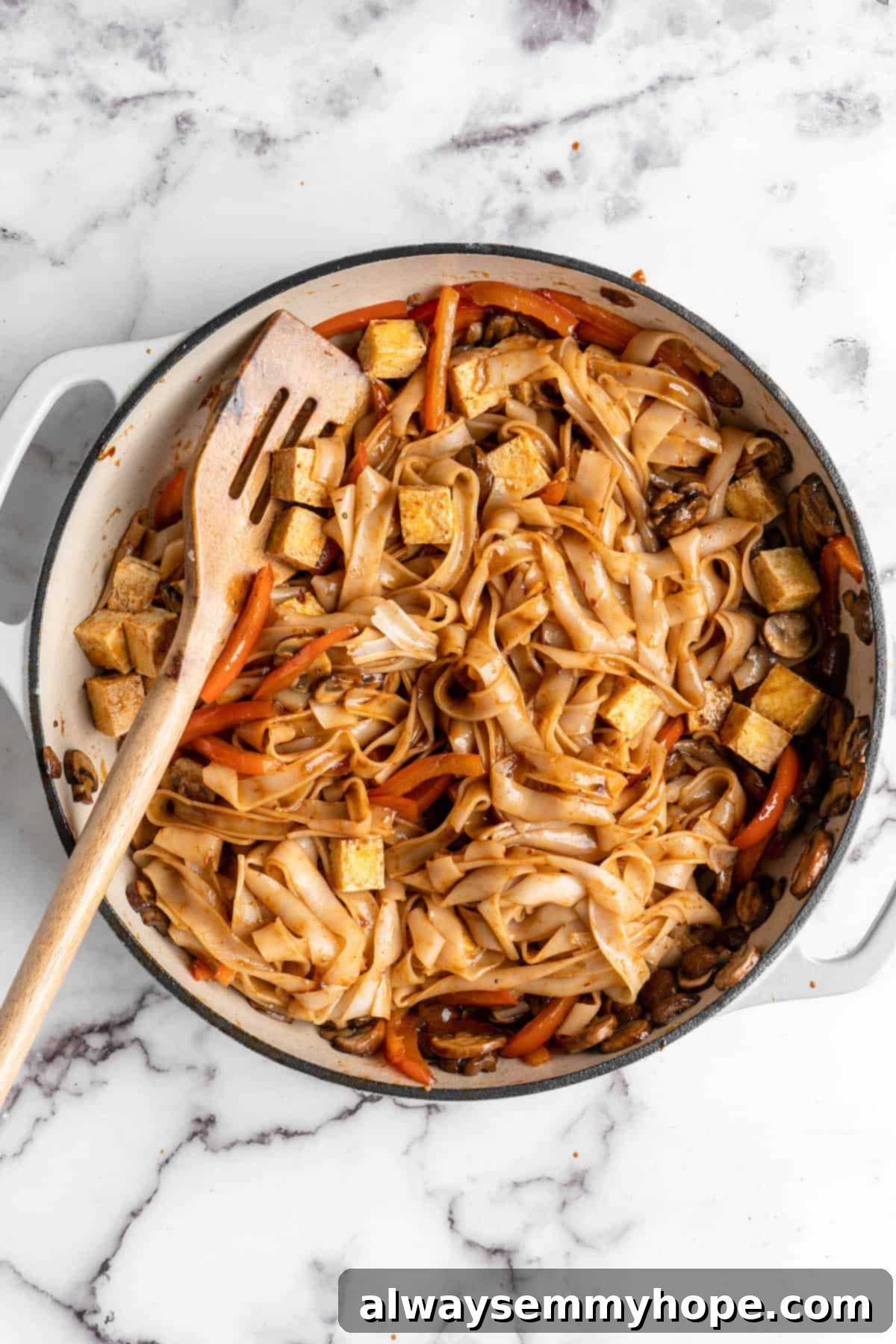Overhead view of vegan Pad Thai in skillet after adding noodles and sauce