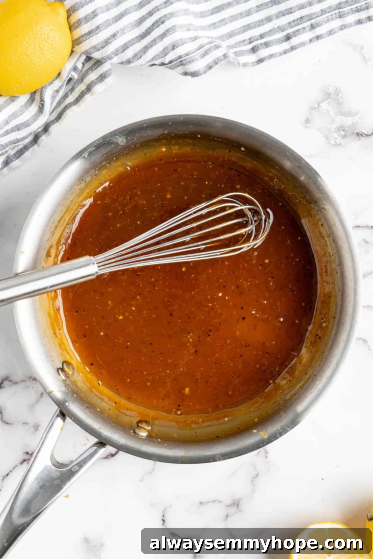 This lemon pepper tofu is crispy and saucy, with the perfect chewy texture. It takes minutes to make and it's absolutely packed with flavour! Overhead view of lemon pepper sauce in a pan with a whisk.