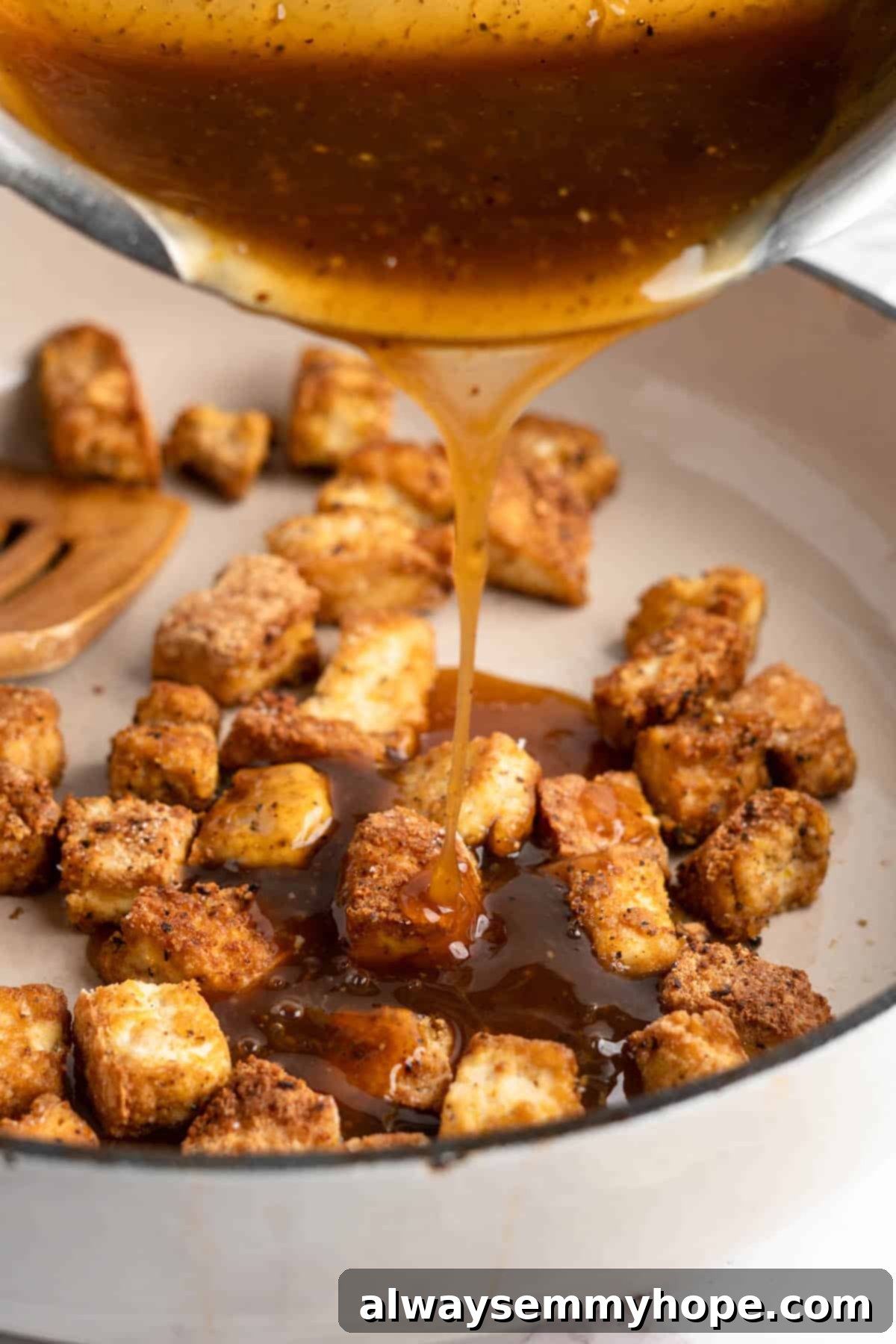 This lemon pepper tofu is crispy and saucy, with the perfect chewy texture. It takes minutes to make and it's absolutely packed with flavour! Pouring sauce over lemon pepper tofu in a skillet.