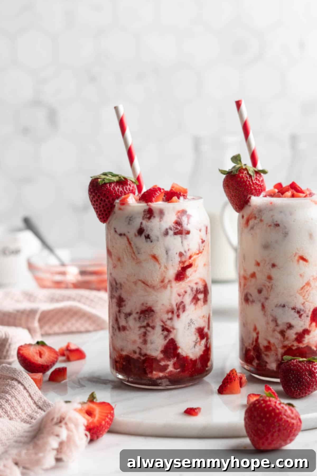 How to make vegan Korean strawberry milk! This easy recipe is made with 4 simple ingredients and each glass is full of fresh strawberries. Two glasses of vegan Korean strawberry milk, showing the lovely pink hue and strawberry pieces, ready to be enjoyed.