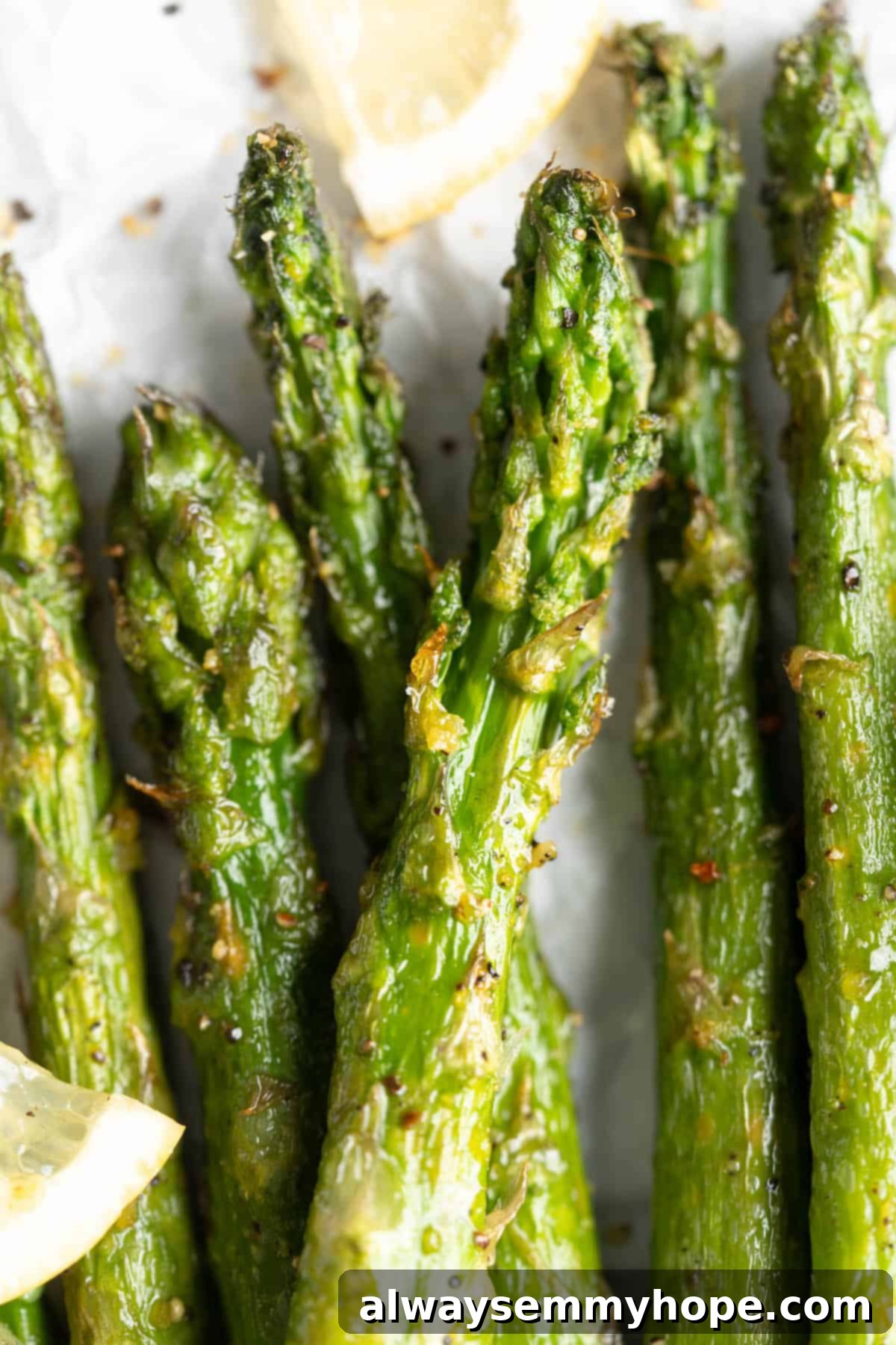 This easy lemon pepper air fryer asparagus is the perfect side dish for busy weeknights. It's done in just 10 minutes from start to finish! A close-up view of perfectly cooked air fryer asparagus, highlighting its crispy tips and tender stalks, seasoned with lemon pepper.