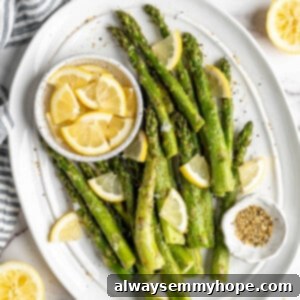 Crispy Air Fryer Asparagus 2 Overhead view of air fryer asparagus on a platter with a bowl of lemon wedges.