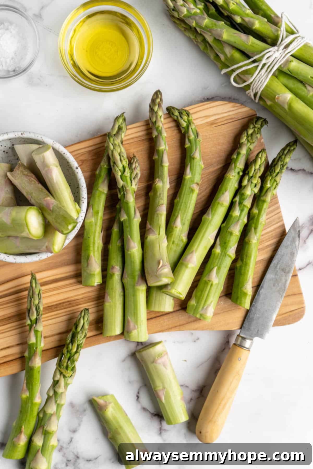 This easy lemon pepper air fryer asparagus is the perfect side dish for busy weeknights. It's done in just 10 minutes from start to finish! Overhead view showing a person trimming the woody ends off asparagus spears.
