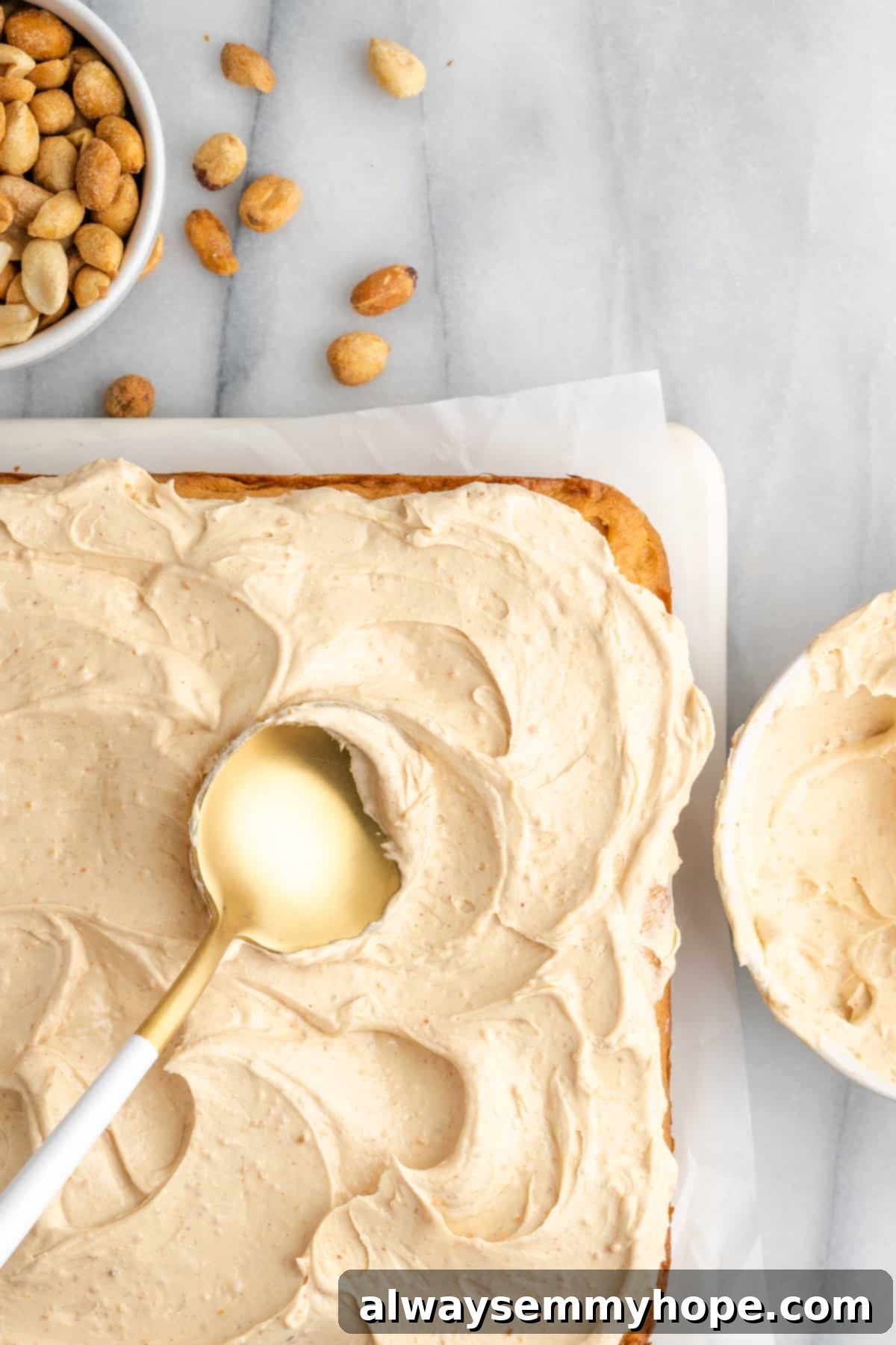 A spatula smoothly spreading rich, creamy peanut butter frosting over the top of a freshly baked vegan peanut butter cake, achieving an even layer.