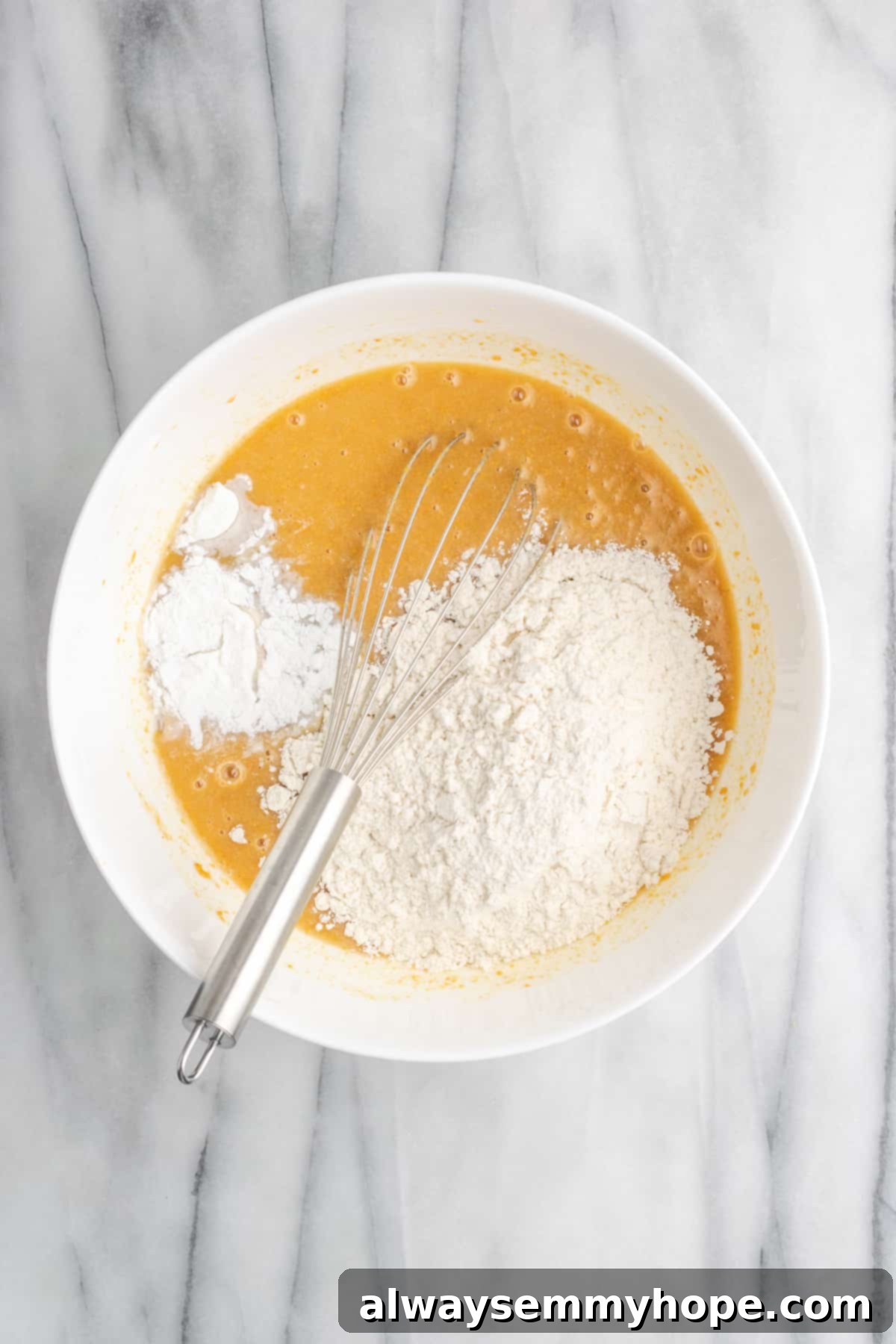 Flour and other dry ingredients being carefully sifted or added into a bowl of wet ingredients for the peanut butter cake batter.