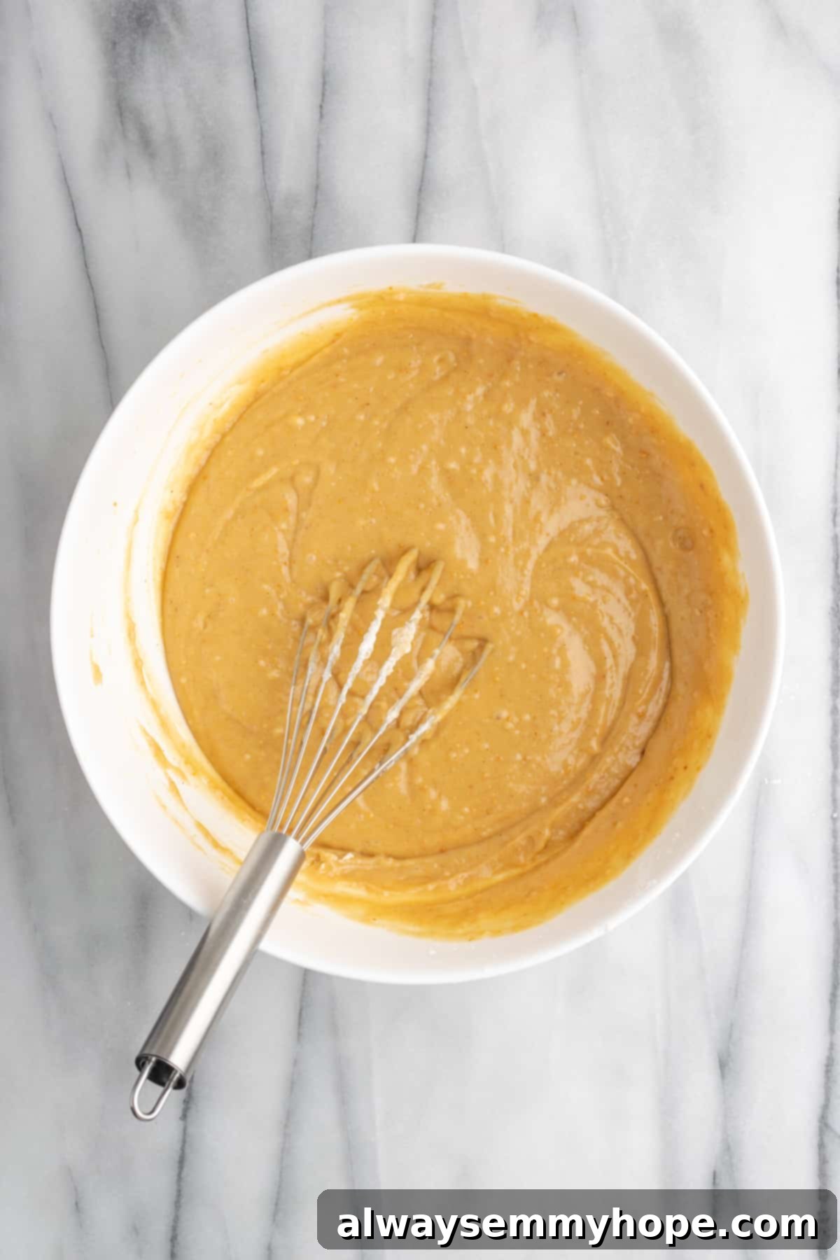 The delightful vegan peanut butter cake batter, perfectly smooth and ready to bake. A close-up of the ready-to-bake vegan peanut butter cake batter poured into a parchment-lined baking pan, smoothed evenly with a spatula.