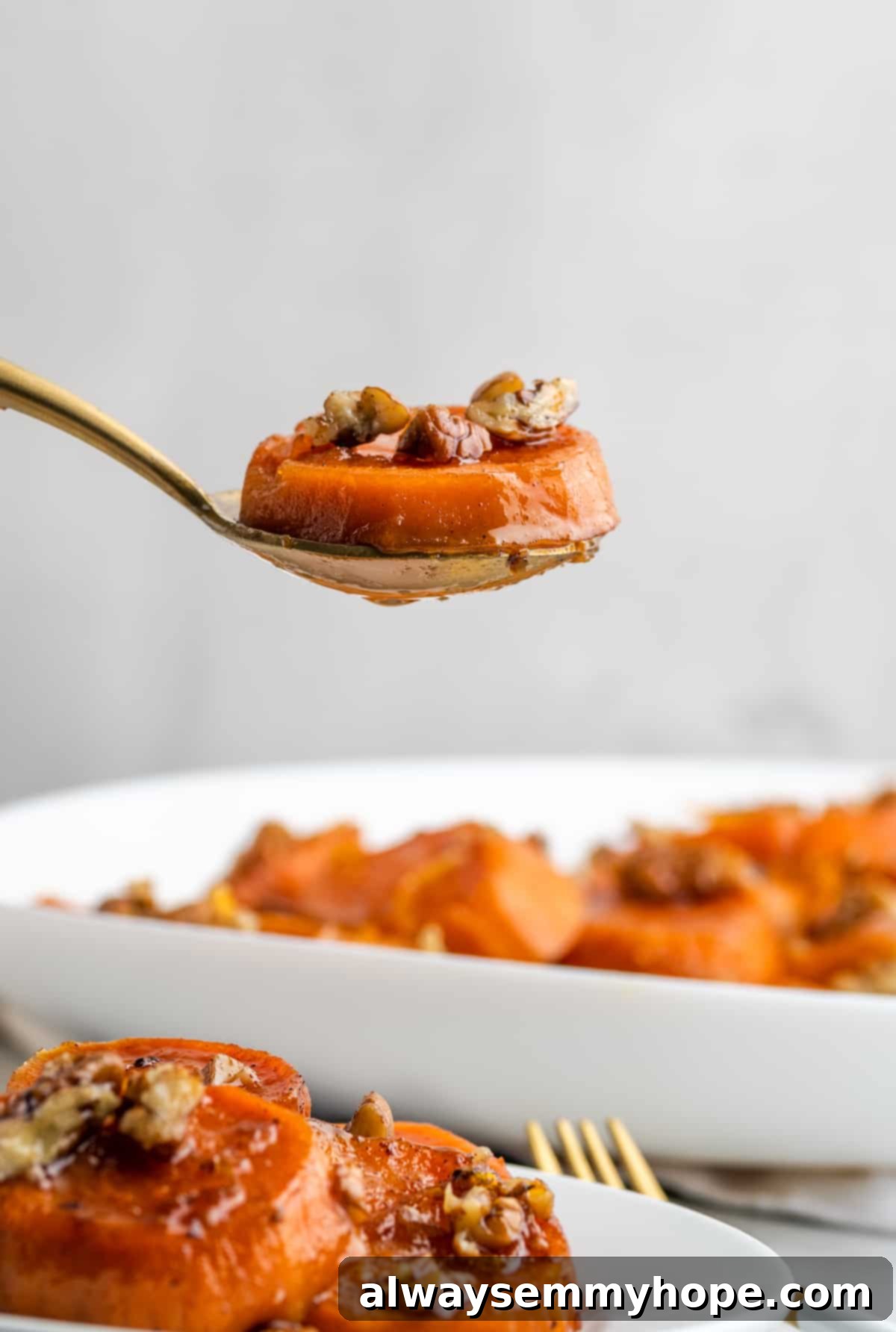 A single piece of delicious candied yam on a fork, showcasing its texture. A close-up of a single tender piece of candied yam on a fork, glistening with the sweet, sticky sauce.