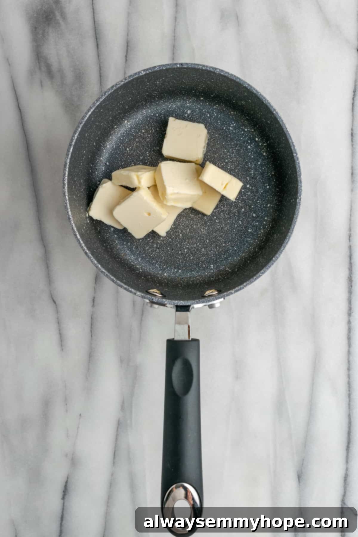 Unmelted vegan butter in a saucepan, ready to be heated for the candied yams sauce. Unmelted vegan butter cubes in a stainless steel saucepan over a burner.