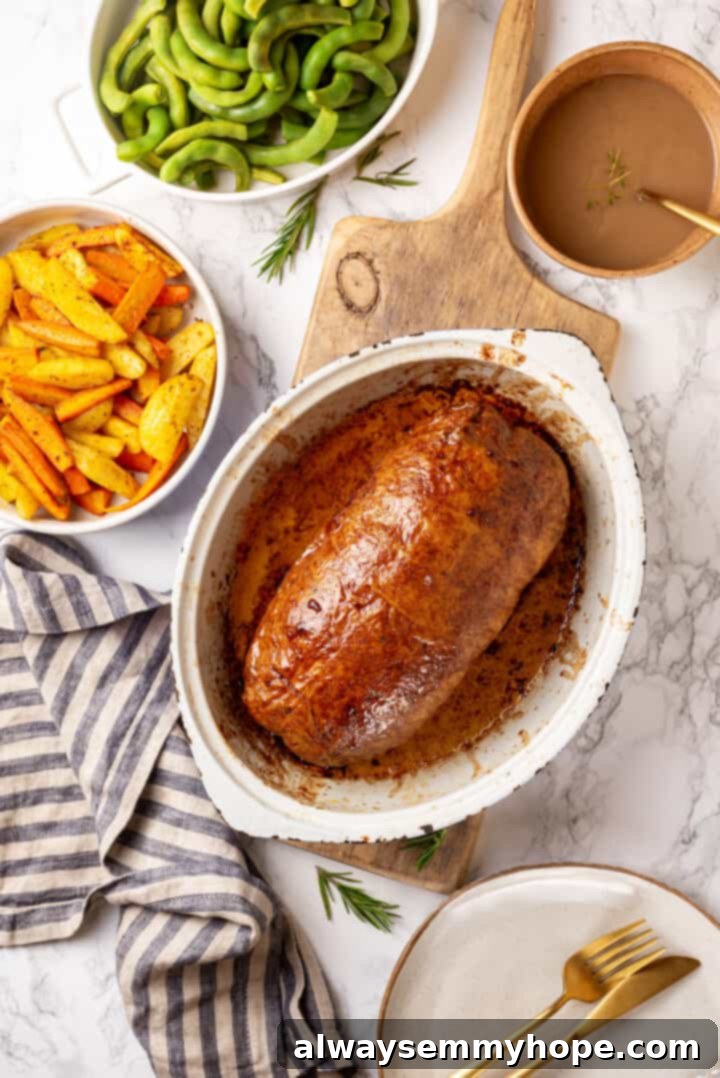 This homemade vegan turkey recipe is supremely flavourful and the perfect addition to any Thanksgiving table or holiday dinner! Overhead view of vegan turkey in baking dish with bowls of gravy, roasted vegetables, and edamame