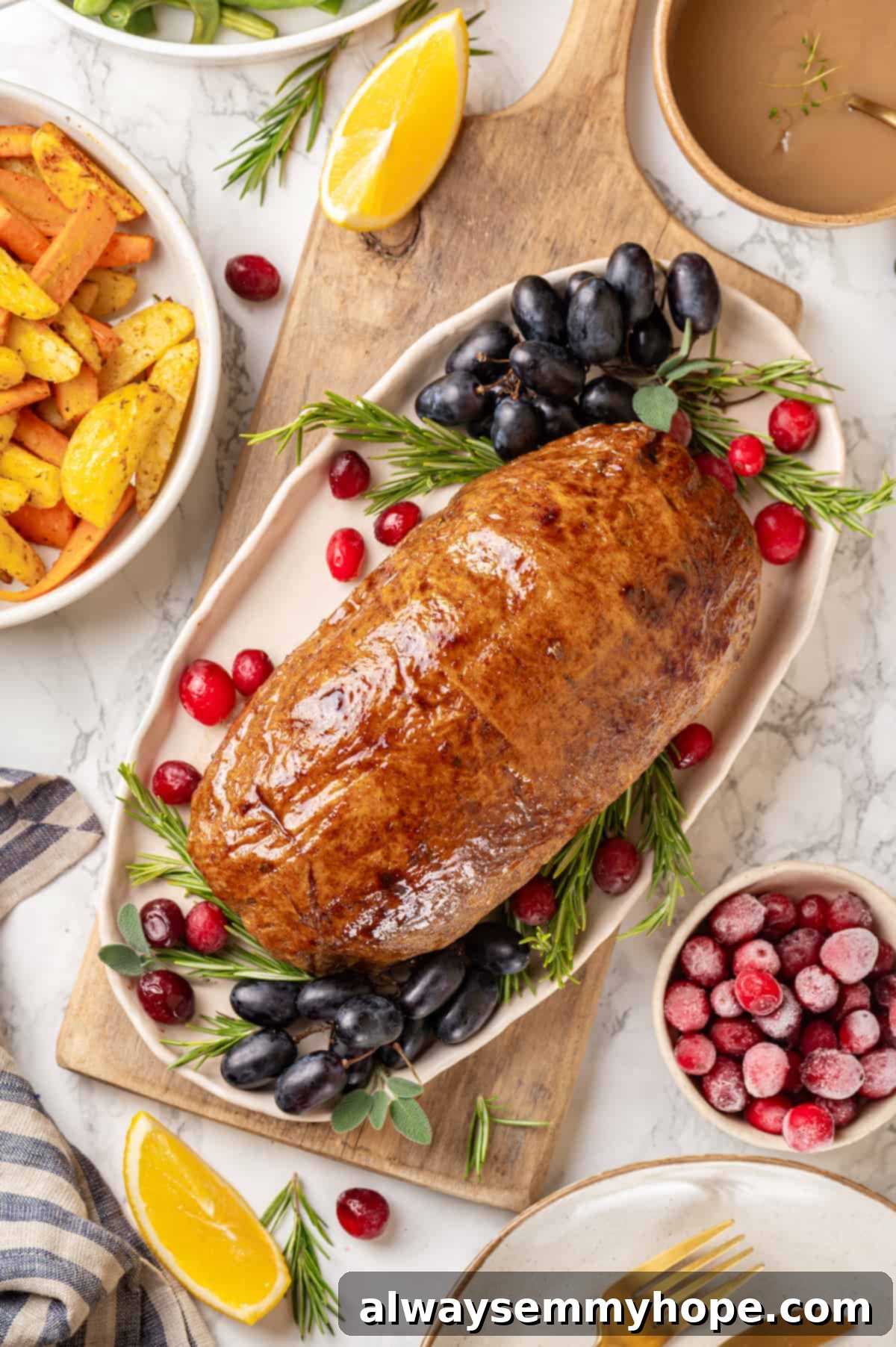 This homemade vegan turkey recipe is supremely flavourful and the perfect addition to any Thanksgiving table or holiday dinner! Overhead view of vegan turkey on platter with rosemary, cranberries, and grapes