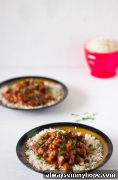 Healthy & Easy Indian Butter Chicken Healthy One-Pan Indian Butter Chicken with coconut milk, served with basmati rice and fresh cilantro on a white plate.