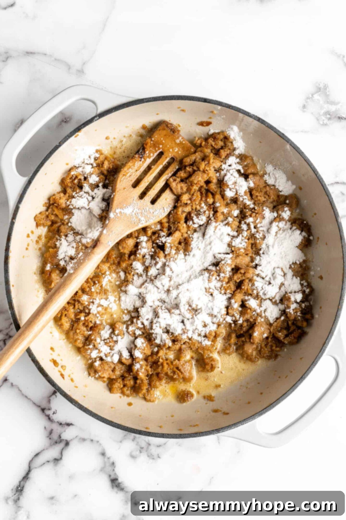 Cooked vegan sausage in a dutch oven, with flour on top, and a slotted wooden spoon