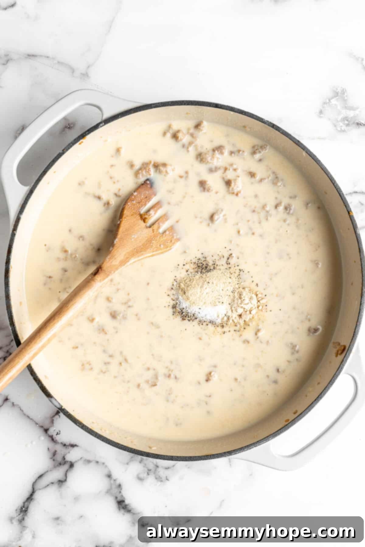 A very wet gravy in a dutch oven with a pile of seasonings on top, and a slotted wooden spoon