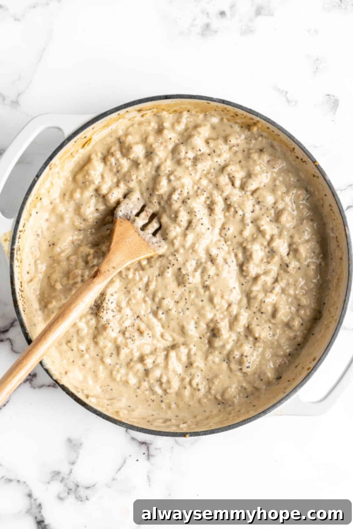 A dutch oven full of thick gravy, and a slotted wooden spoon