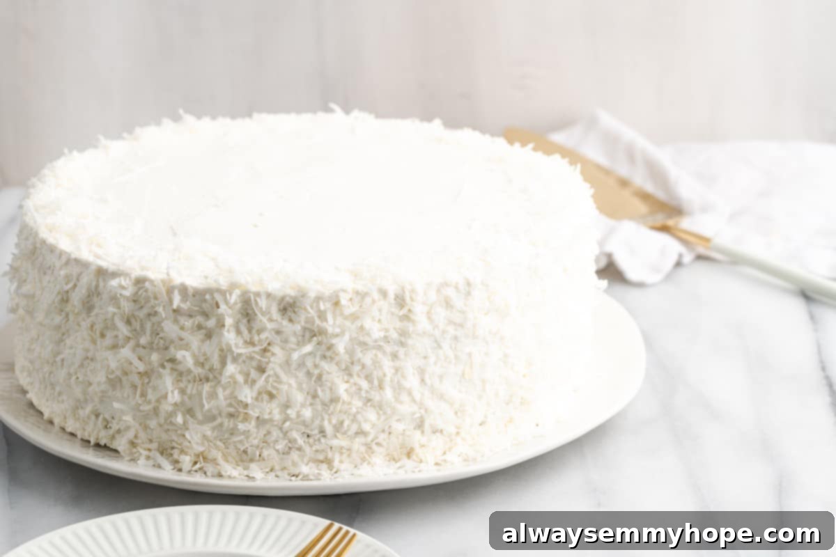 Tropical Vegan Coconut Cake 19 A whole vegan coconut cake with creamy frosting and shredded coconut, ready to be served.