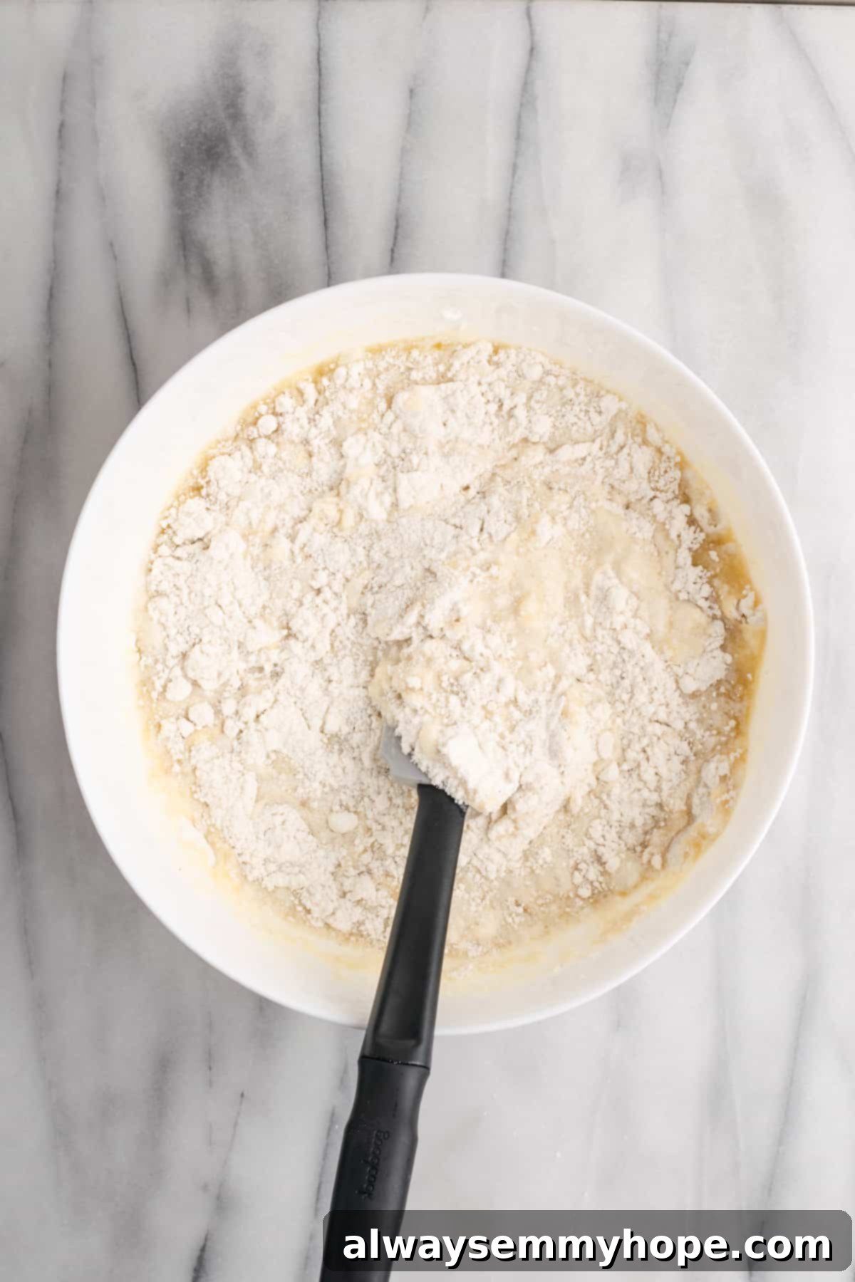 Tropical Vegan Coconut Cake 7 Close-up of vegan coconut cake batter being gently mixed in a bowl until just combined.