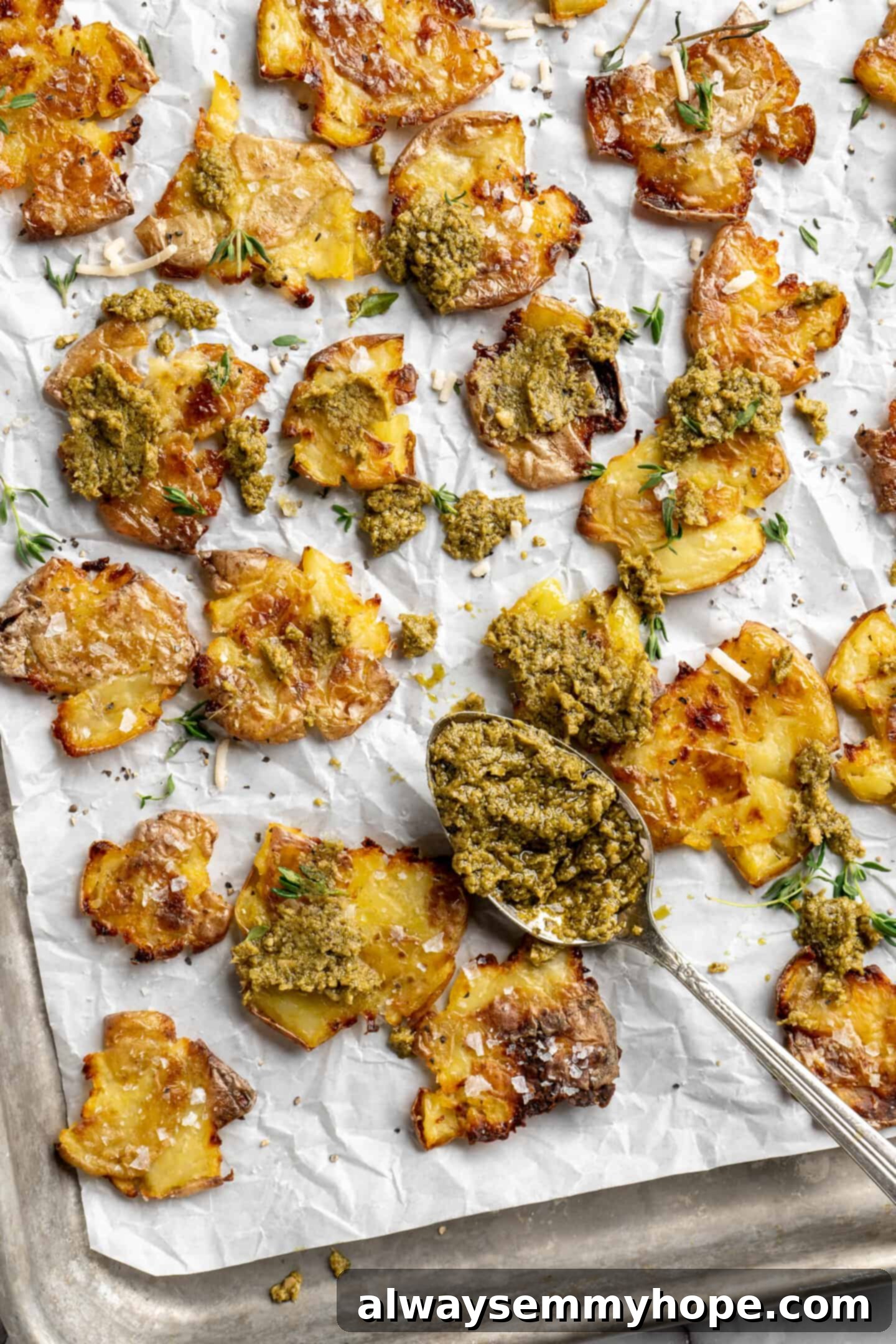 Crispy smashed potatoes on a sheet pan, artfully topped with fresh pesto