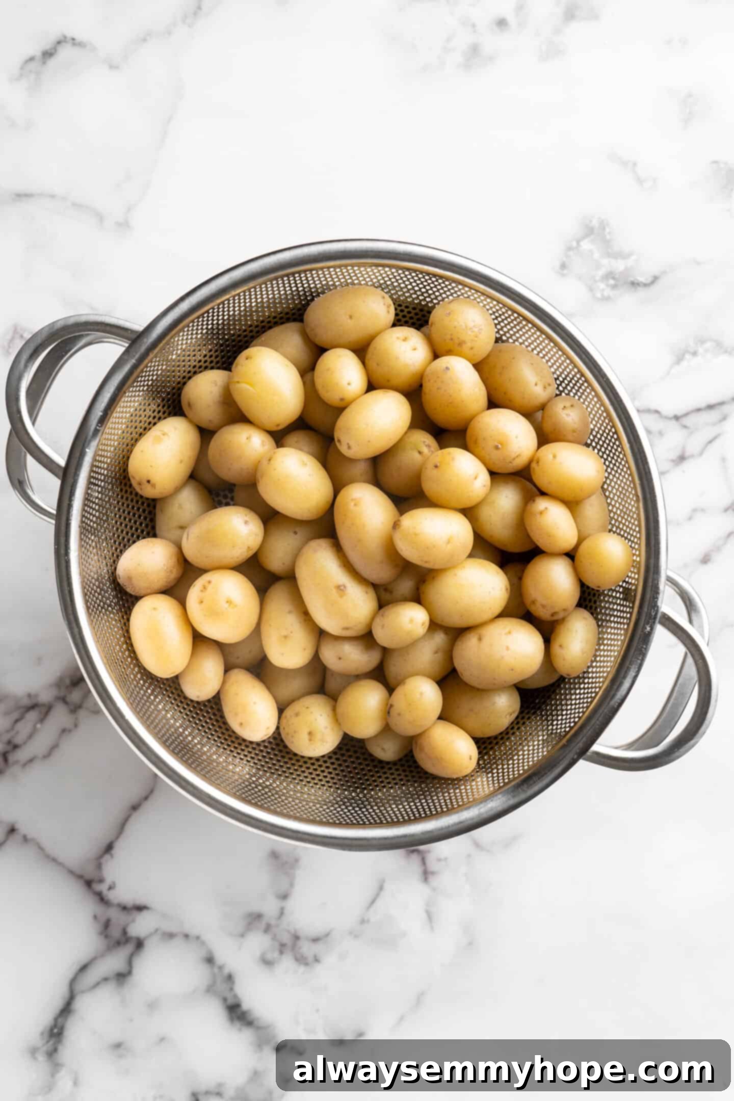 Boiled baby potatoes in a colander, ready for the next step