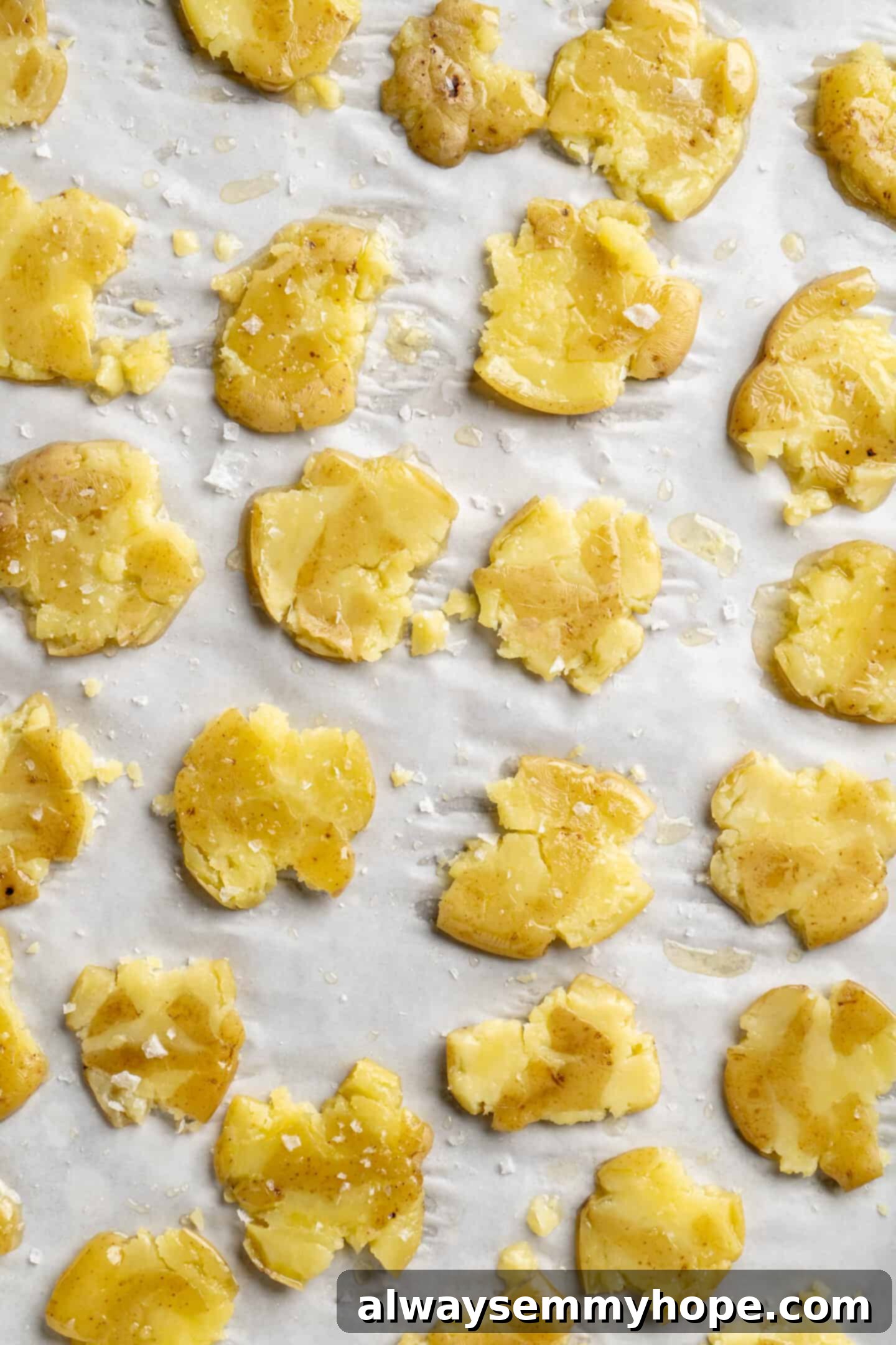 Crushed baby potatoes arranged on a sheet pan before baking