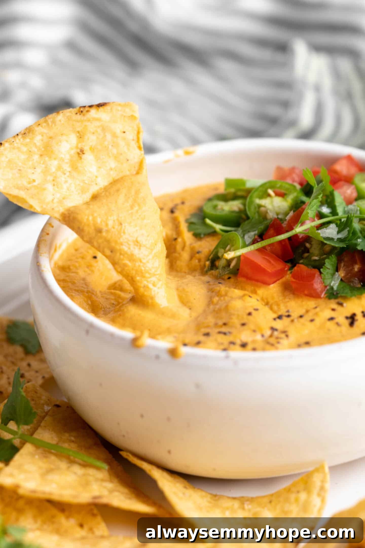 dipping chips in vegan queso Dipping a tortilla chip into vegan queso