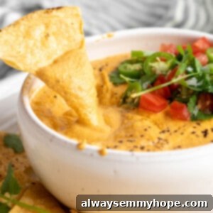 Velvety Plant-Based Queso 2 Dipping a tortilla chip into vegan queso